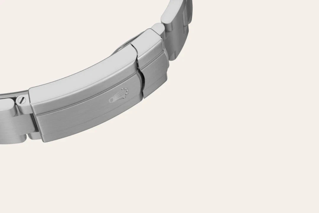 Close-up of a polished stainless steel watch bracelet clasp, showcasing a subtle embossed logo on a smooth, brushed metal surface, highlighting fine craftsmanship and attention to detail.