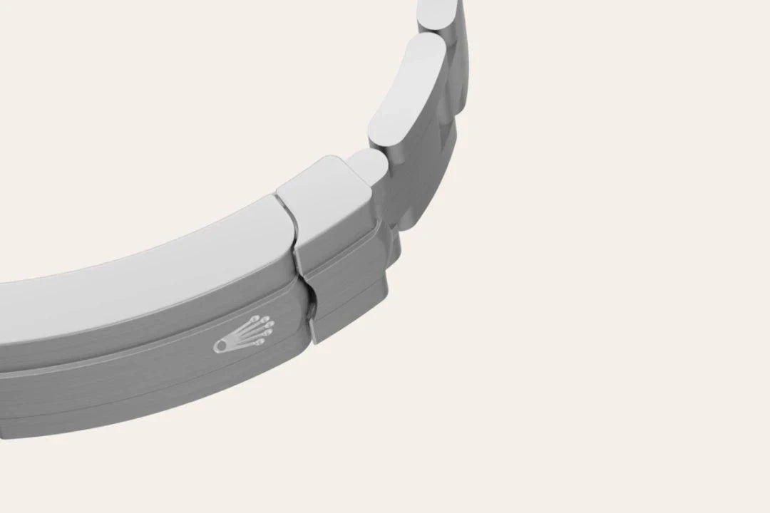 Close-up of a silver-tone metal watch bracelet clasp featuring a subtle embossed logo, highlighting fine craftsmanship and attention to detail.