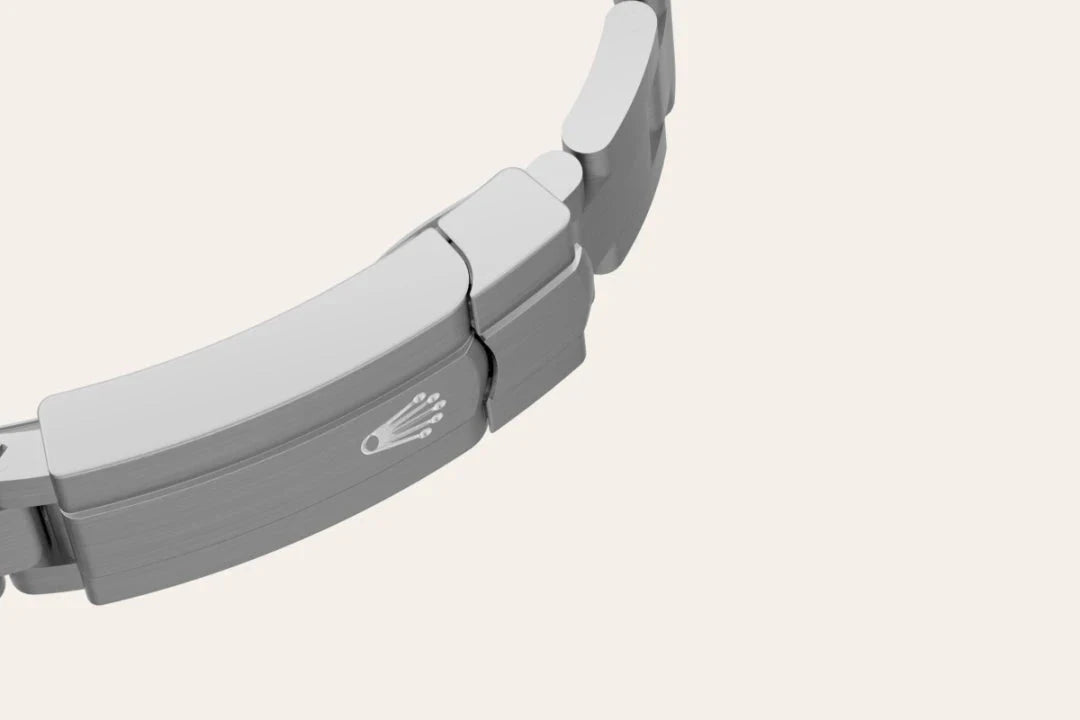 Close-up view of a silver metal watch bracelet clasp featuring a polished emblem, highlighting fine craftsmanship and attention to detail by a family-owned jeweler.
