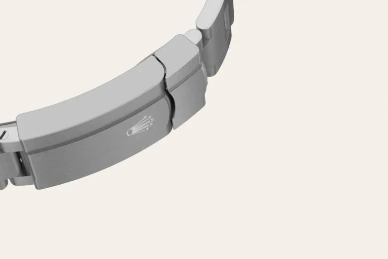 Close-up of a sleek stainless steel watch bracelet clasp featuring an engraved crown logo, highlighting fine craftsmanship and luxury watch design.