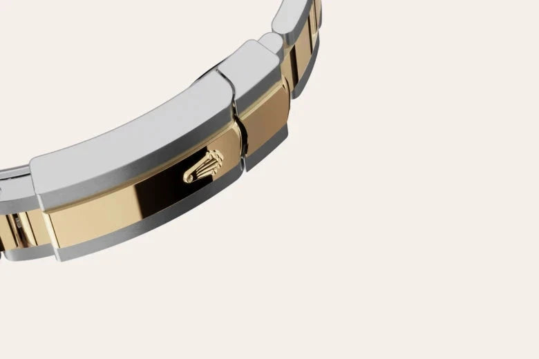 Close-up of a two-tone metal watch bracelet clasp featuring a raised crown logo, highlighting fine craftsmanship and elegant design in luxury jewelry.
