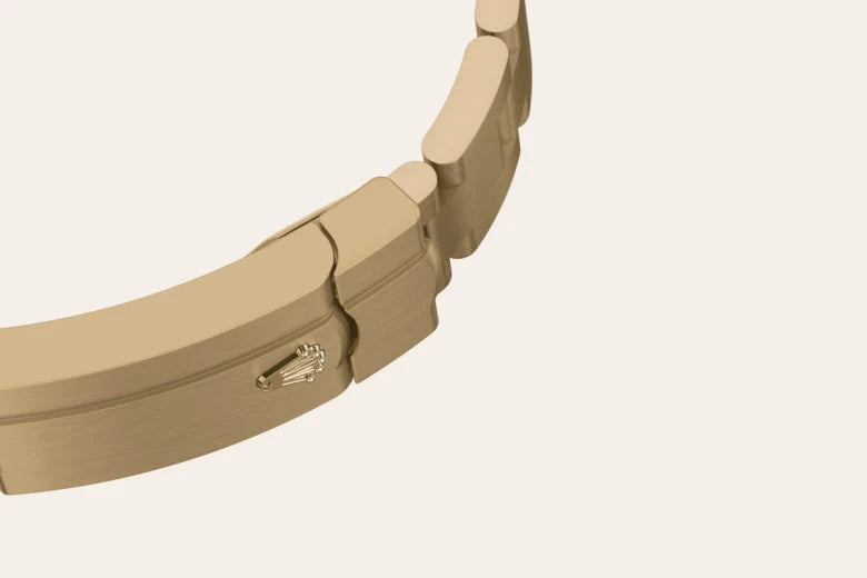 Close-up of a gold watch bracelet clasp featuring a subtle embossed Rolex crown logo, highlighting fine craftsmanship and luxury jewelry design.