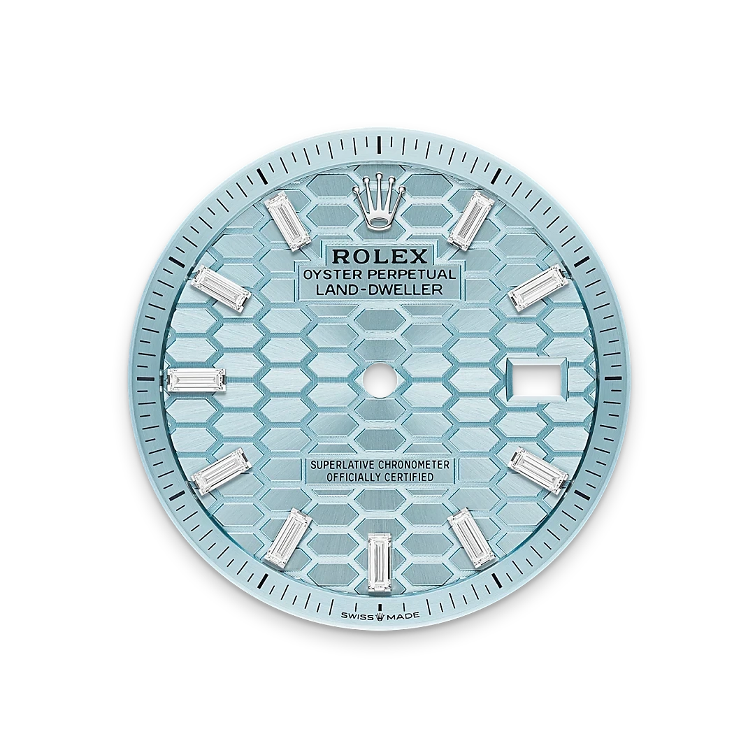 Close-up of a light blue Rolex Land-Dweller watch dial with a textured hexagonal pattern, diamond hour markers, and the signature Rolex crown logo at the top.
