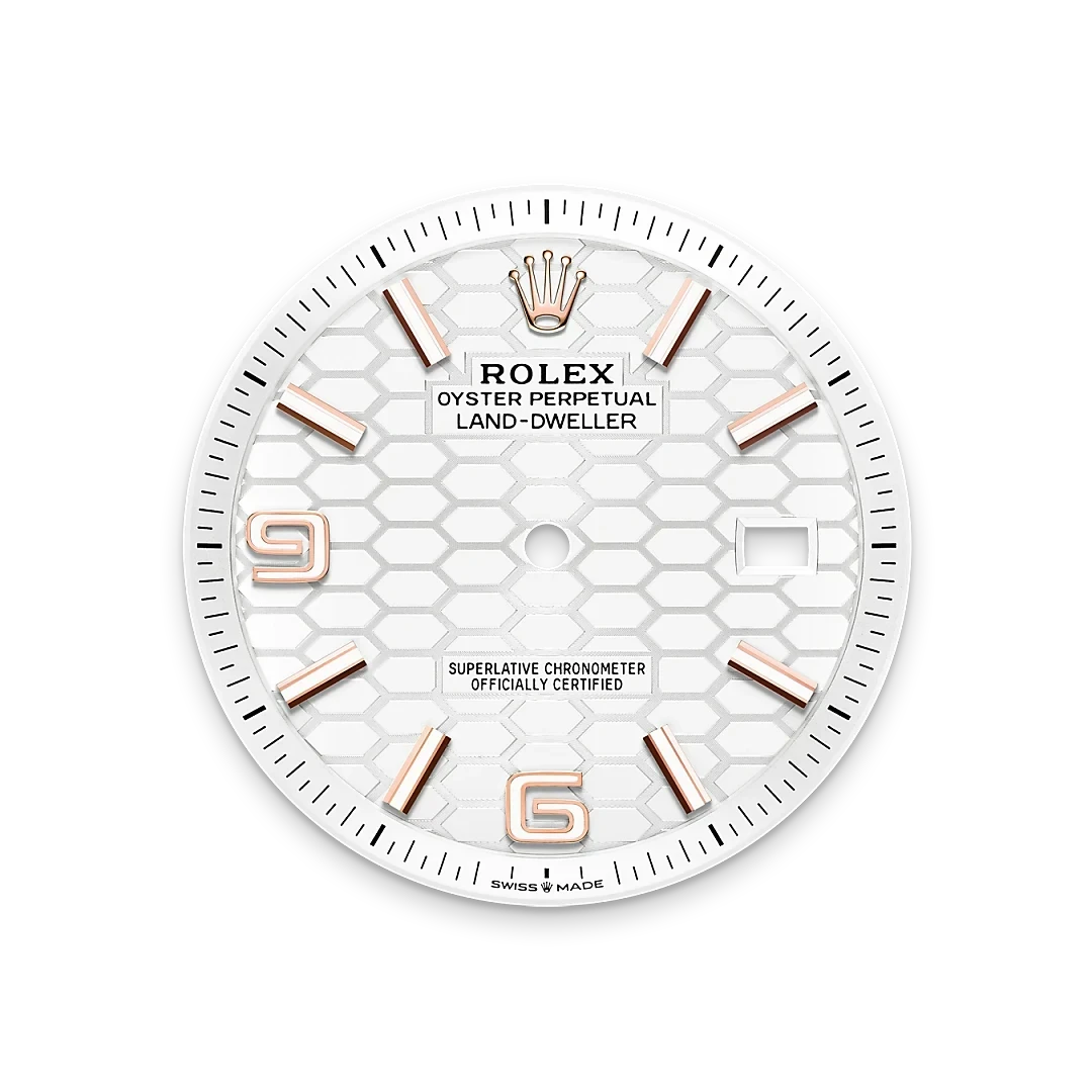 White Rolex Land-Dweller watch face with rose gold hour markers, hexagonal pattern background, and text indicating Oyster Perpetual and certified chronometer status.