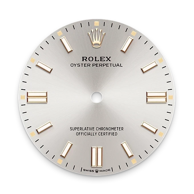 Close-up of a silver Rolex Oyster Perpetual watch dial with gold hour markers, the Rolex crown logo at 12 o'clock, and text indicating it is a superlative chronometer officially certified.