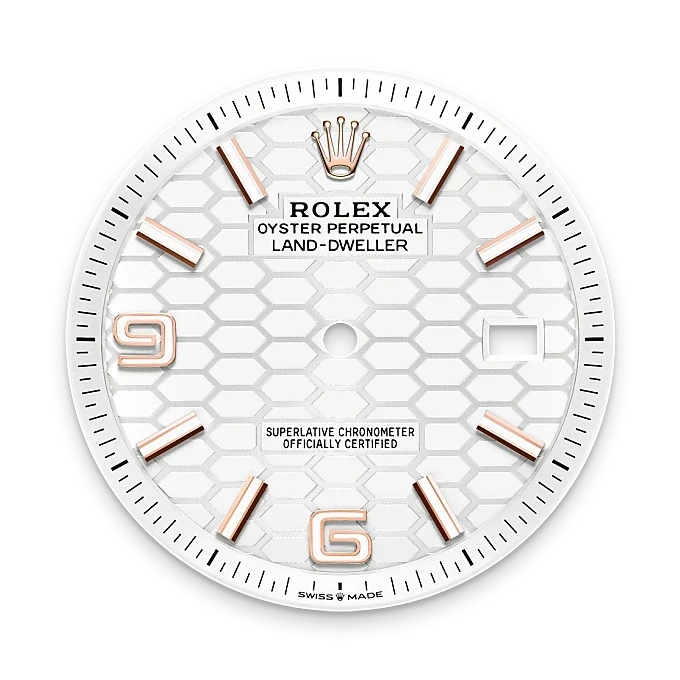 Close-up of a Rolex Land-Dweller watch dial featuring a white honeycomb pattern, rose gold hour markers, Rolex crown logo, and a date window at 3 o’clock, symbolizing luxury jewelry and precision craftsmanship.