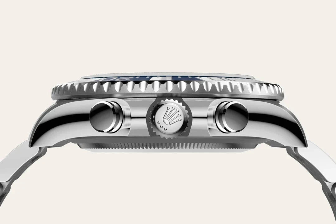 Close-up side view of a luxury wristwatch case showing the crown and push buttons, highlighting fine craftsmanship and polished metal finishes on a light background.