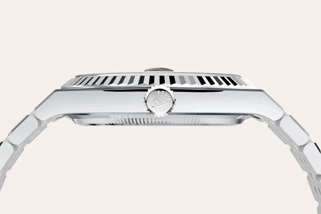 Side profile close-up of a luxury silver-toned wristwatch showcasing its fluted bezel, crown, and linked metal bracelet against a plain light background.