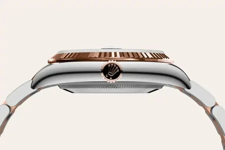 Close-up side view of a luxury watch case with a rose gold bezel and a polished silver body, featuring a detailed crown with a classic emblem.