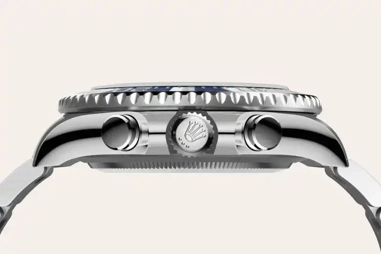 Close-up side view of a polished luxury watch case featuring a detailed crown with the Rolex logo, two push buttons, and a ridged bezel, highlighting fine craftsmanship.