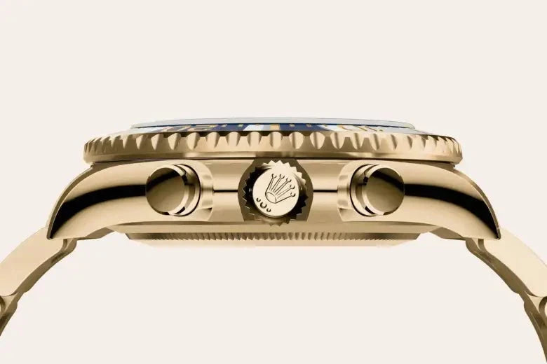 Close-up side view of a gold luxury watch case featuring the Rolex crown logo on the crown with two push buttons on either side, highlighting fine craftsmanship and design.