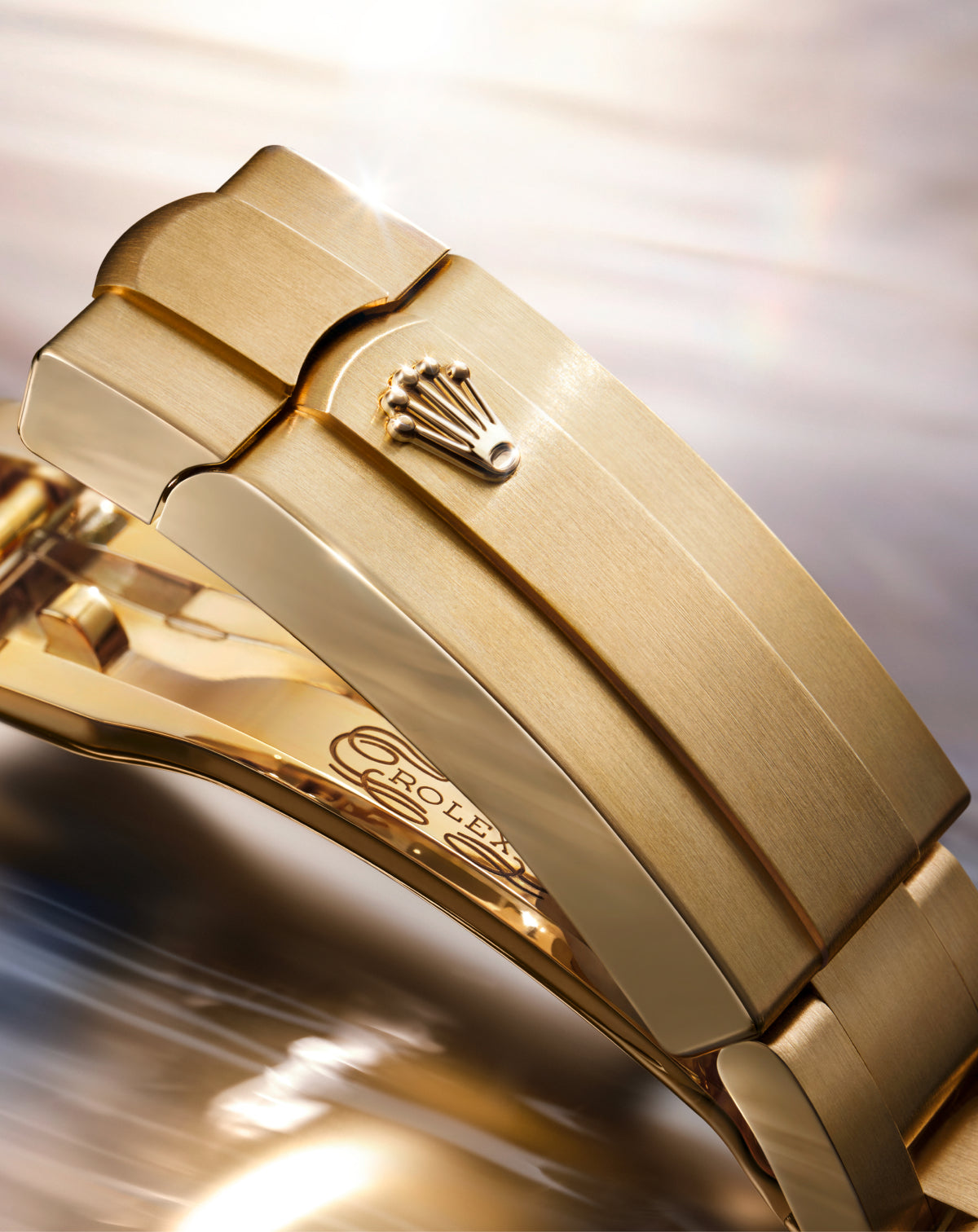 Close-up of a luxury gold watch clasp featuring the engraved Rolex crown emblem and polished finish, highlighting fine craftsmanship and elegant design.