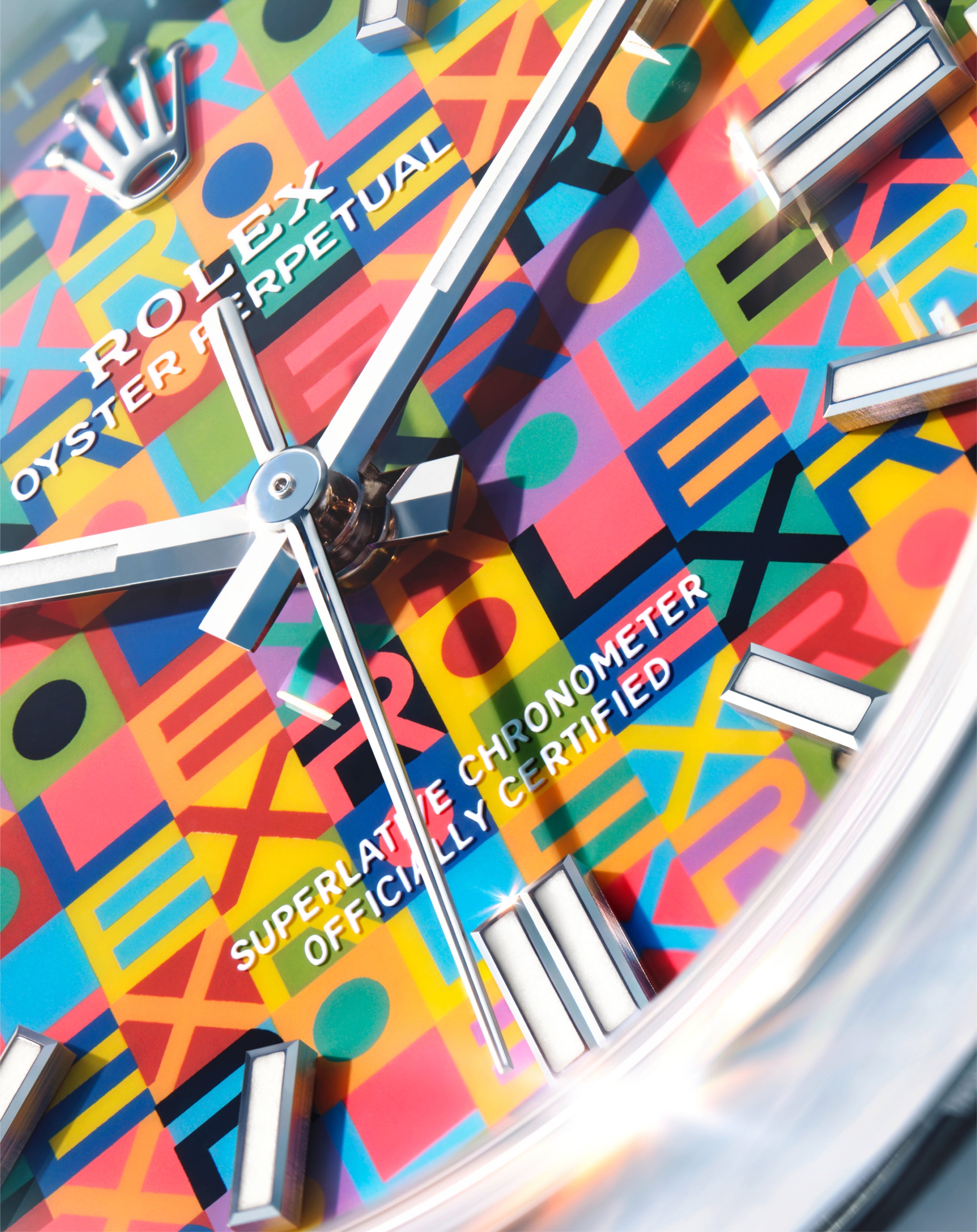 Close-up of a Rolex watch face with a colorful geometric pattern background featuring letters and shapes, showcasing luxury craftsmanship and precision timekeeping.