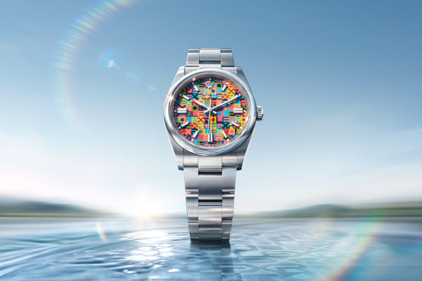 A luxury silver wristwatch with a colorful, intricate dial featuring various flags, displayed standing upright on a reflective water surface with a clear sky background, suggesting elegance and craftsmanship.