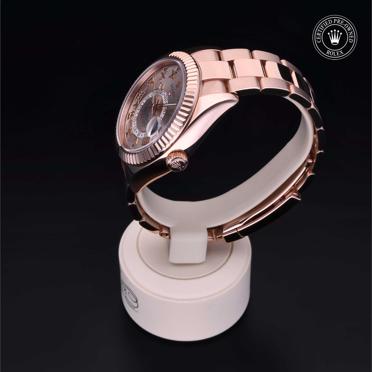 Rose gold Rolex watch displayed on a white stand with a dark background, featuring the Rolex Certified Pre-Owned logo in the top right corner.