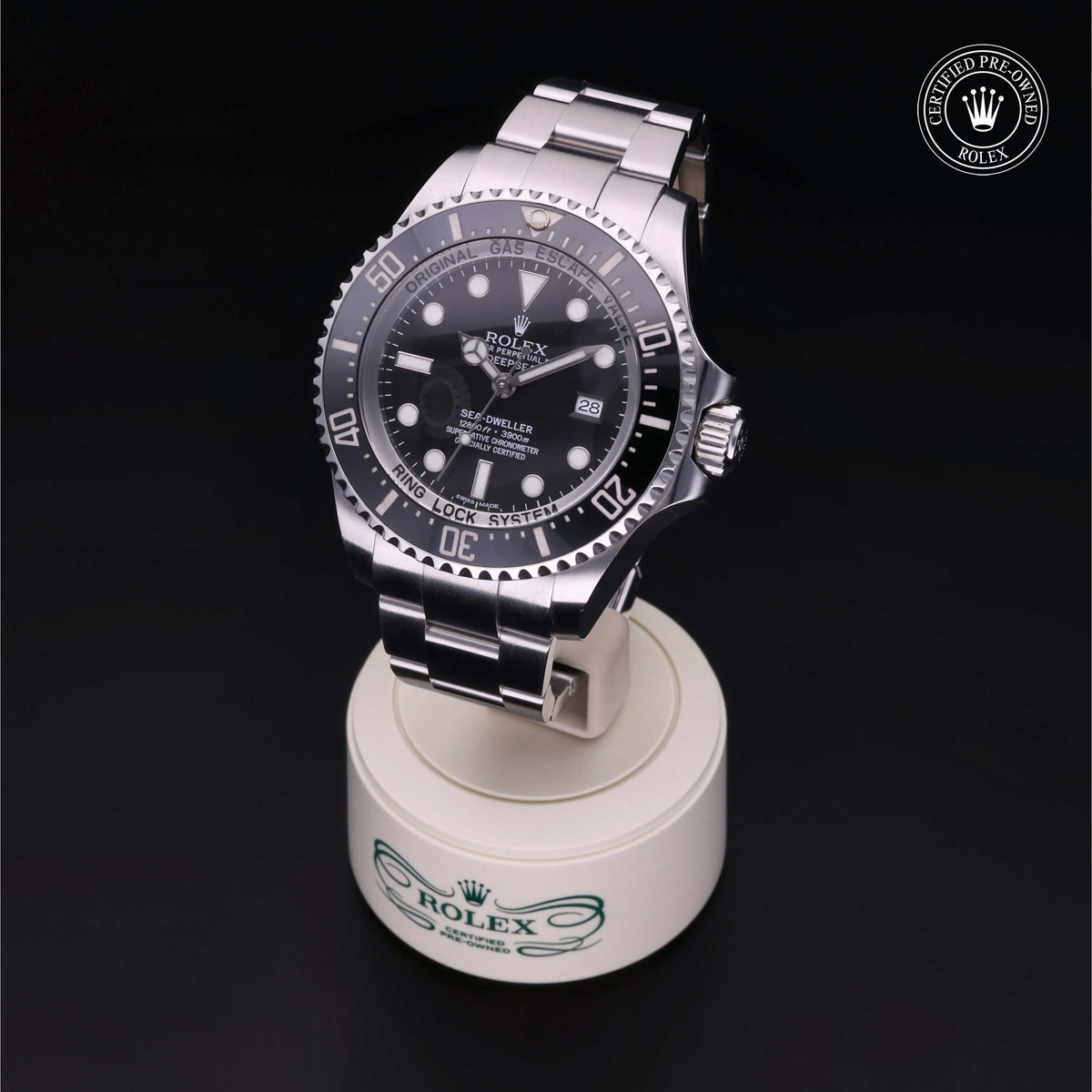 Close-up of a stainless steel Rolex Sea-Dweller luxury watch displayed on a branded stand with a black background, highlighting its detailed dial and bezel craftsmanship.