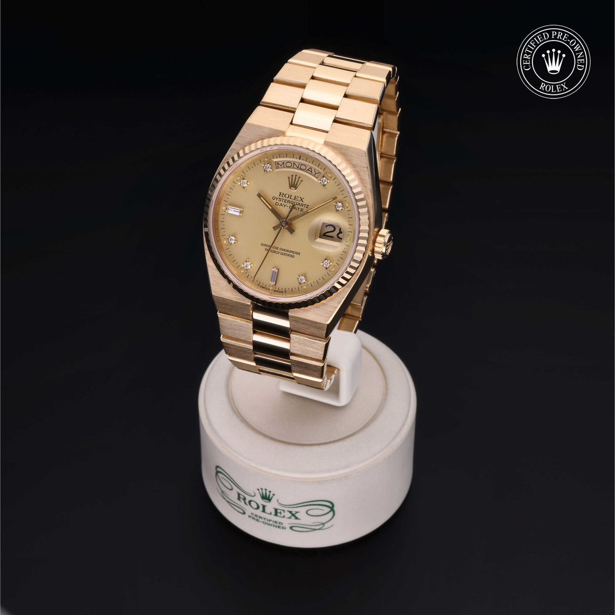Gold Rolex wristwatch with diamond hour markers displayed on a branded stand, highlighted as a certified pre-owned luxury watch by Henne Jewelers, a family-owned jeweler.