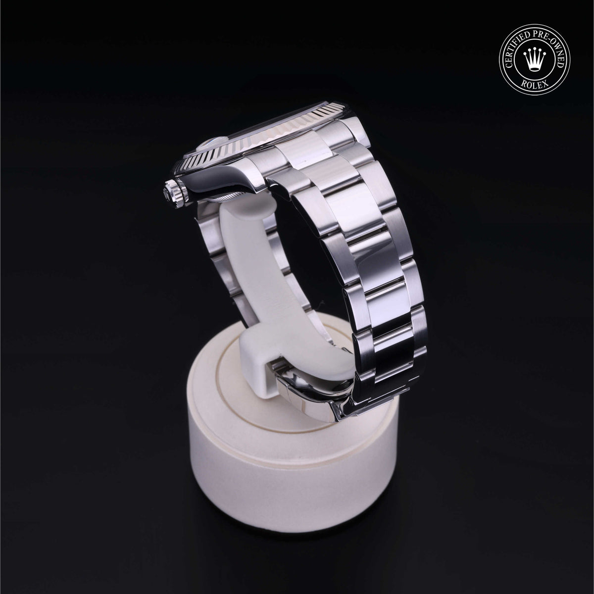Silver stainless steel Rolex watch bracelet displayed on a white stand against a black background with a certified pre-owned Rolex logo in the corner.