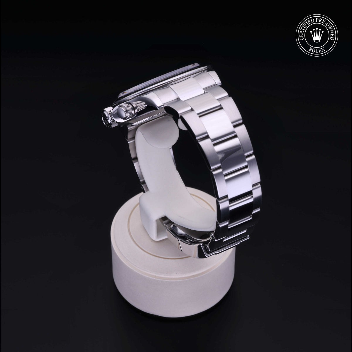 Side view of a stainless steel Rolex luxury watch band displayed on a white stand against a black background, featuring the Rolex Certified Pre-Owned logo.
