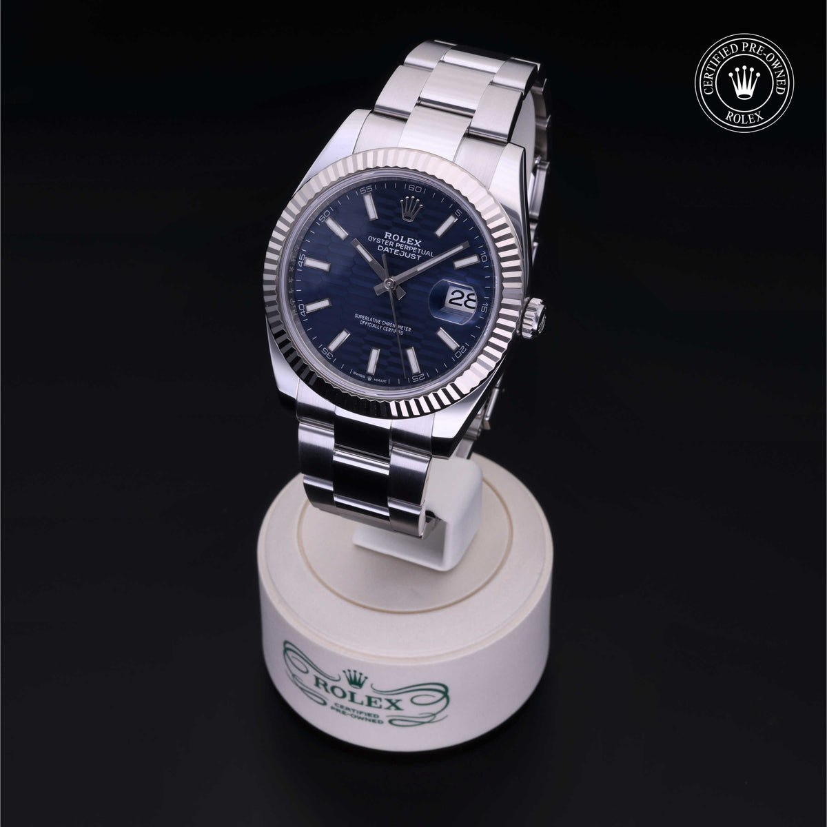 Rolex Certified Pre-Owned Datejust watch with silver metal bracelet and blue dial displayed on branded stand, highlighting luxury watch craftsmanship and quality.