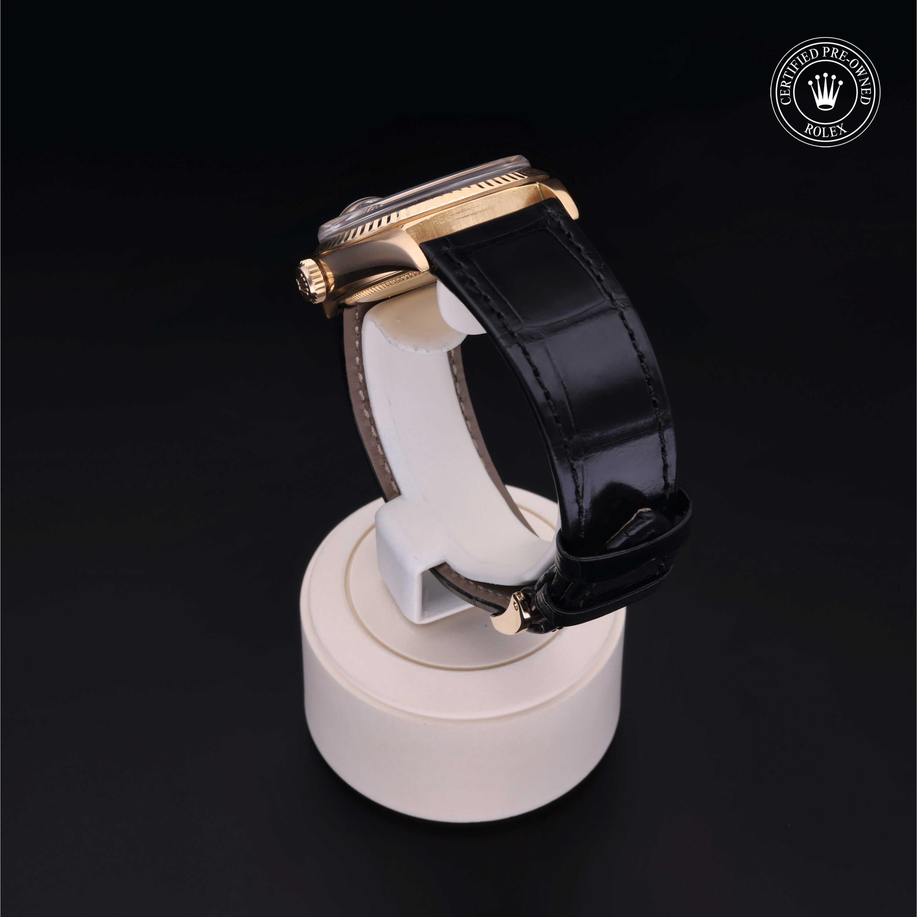 Side view of a Rolex luxury watch with a black leather strap displayed on a white stand against a black background, featuring the Rolex Certified Pre-Owned logo.