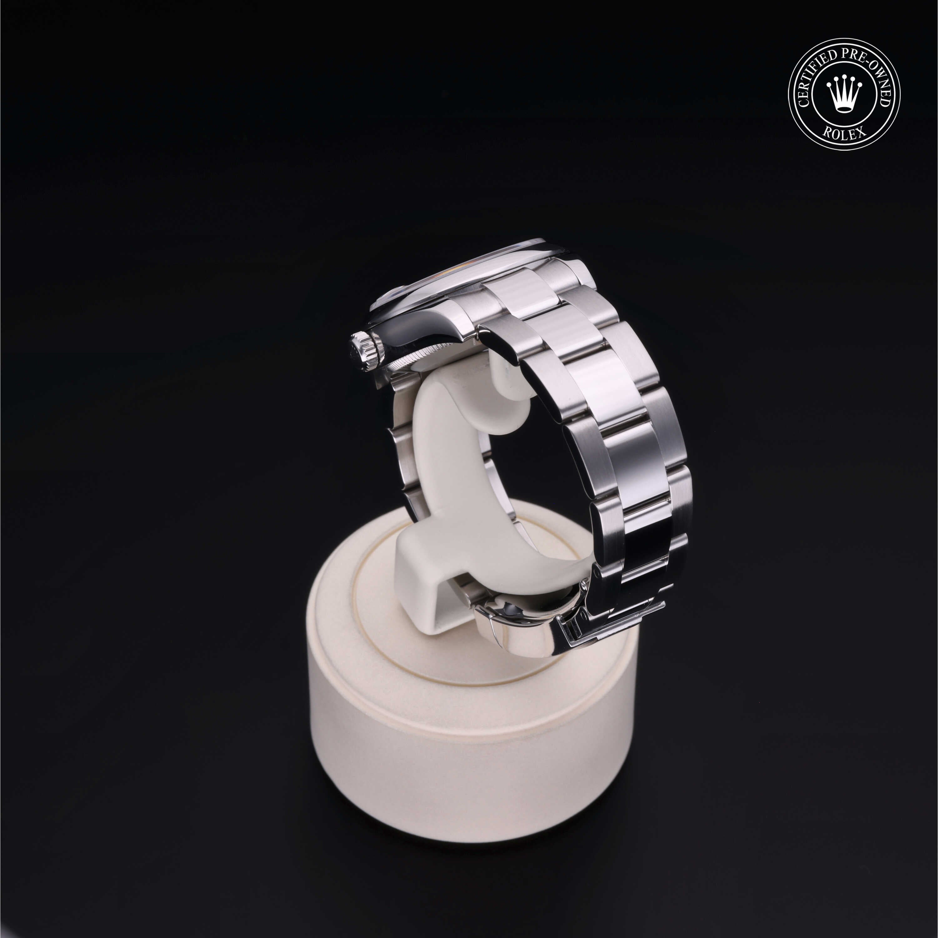 Close-up of a stainless steel Rolex watch band displayed on a white stand with a black background and a 