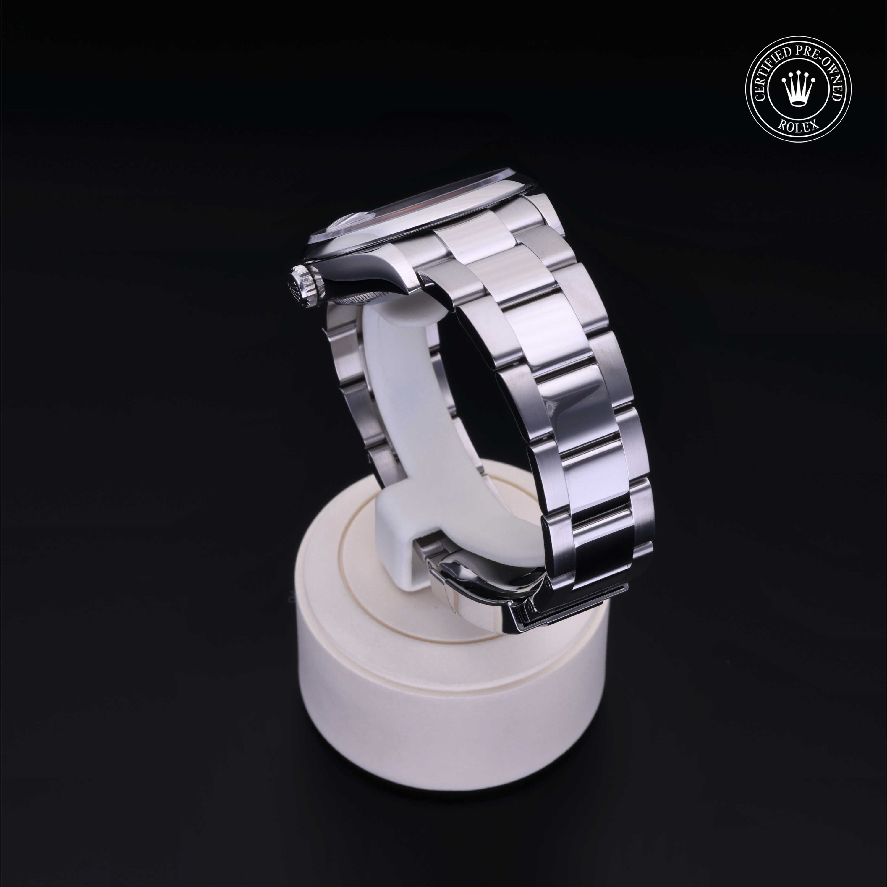 Close-up of a polished stainless steel Rolex watch bracelet displayed on a white stand against a black background, featuring the Rolex Certified Pre-Owned logo.