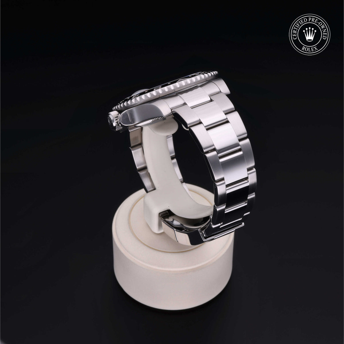 A close-up side view of a polished silver Rolex watch band displayed on a beige stand, accompanied by a Certified Pre-Owned Rolex logo, highlighting fine luxury watch craftsmanship.