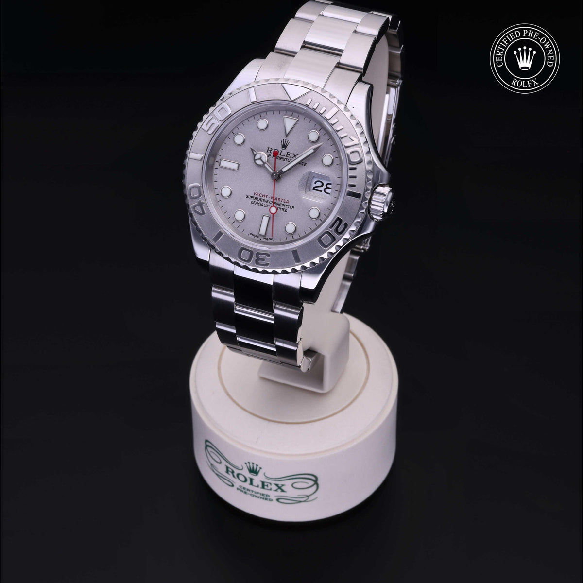 Silver Rolex luxury watch with a stainless steel bracelet displayed on a white stand, featuring a date window and certified pre-owned Rolex emblem.