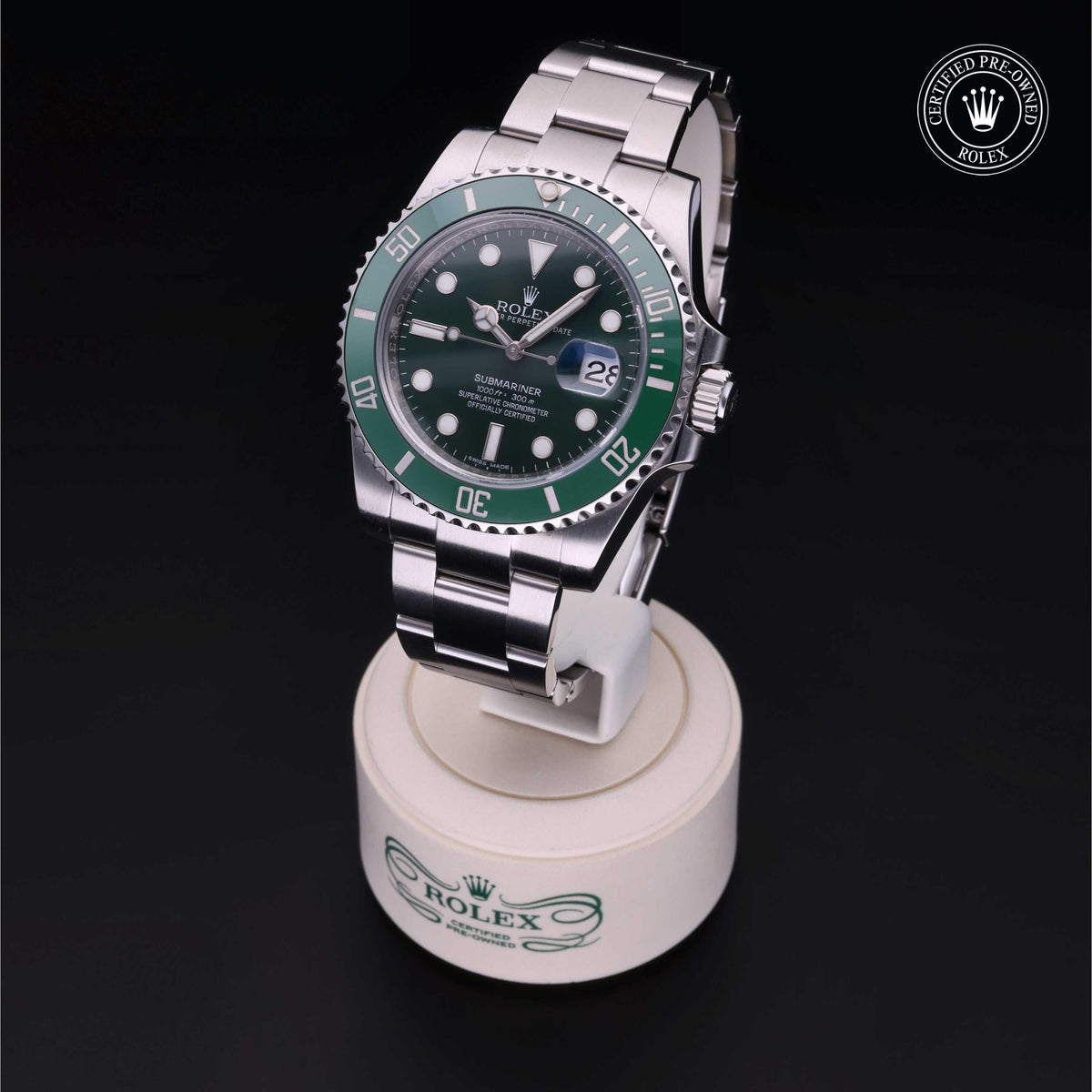Rolex Submariner luxury watch with green bezel and black dial displayed on a white stand, featuring the Rolex Certified Pre-Owned logo in the corner.