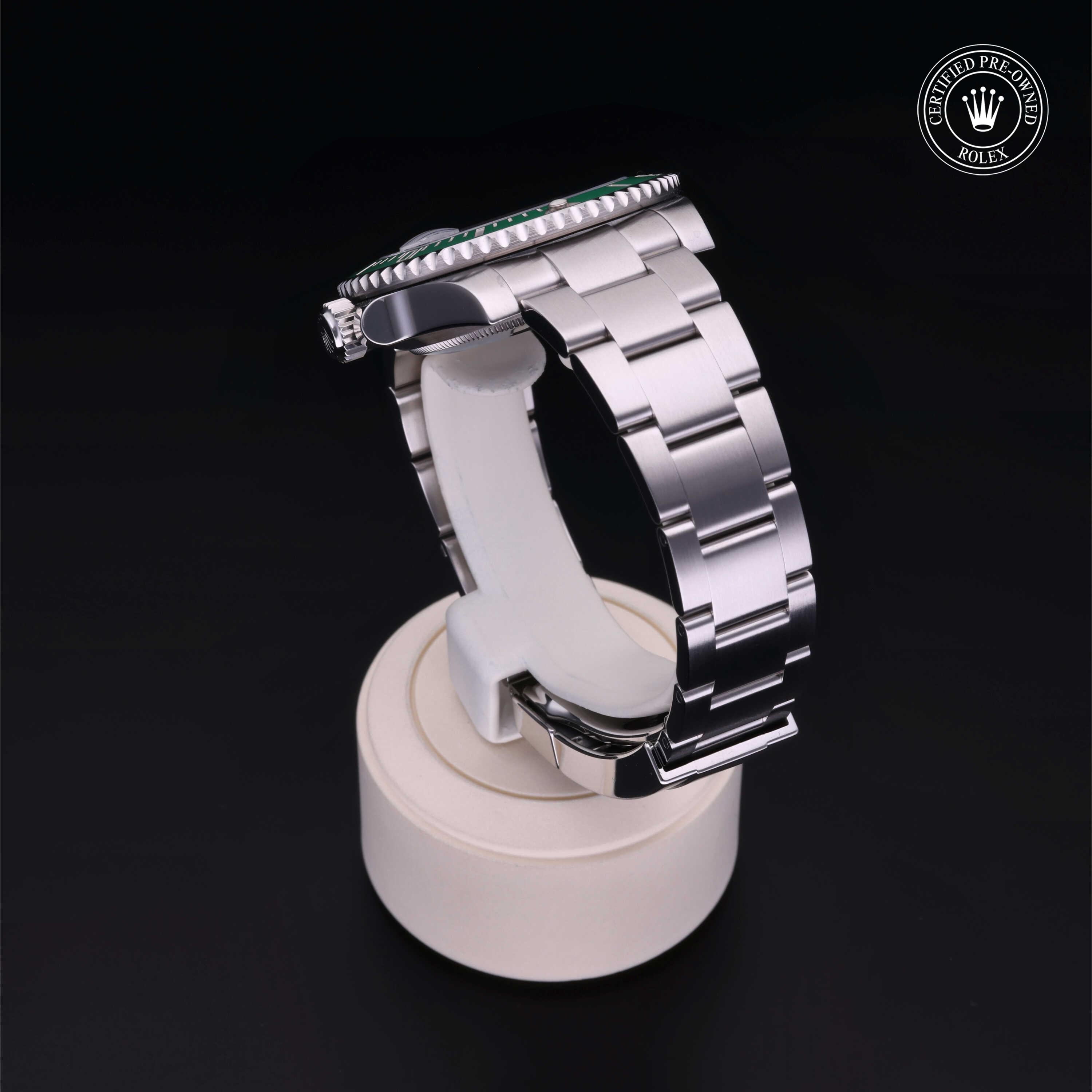Side view of a luxury stainless steel Rolex watch displayed on a white stand against a black background, featuring the certified pre-owned Rolex logo in the corner.
