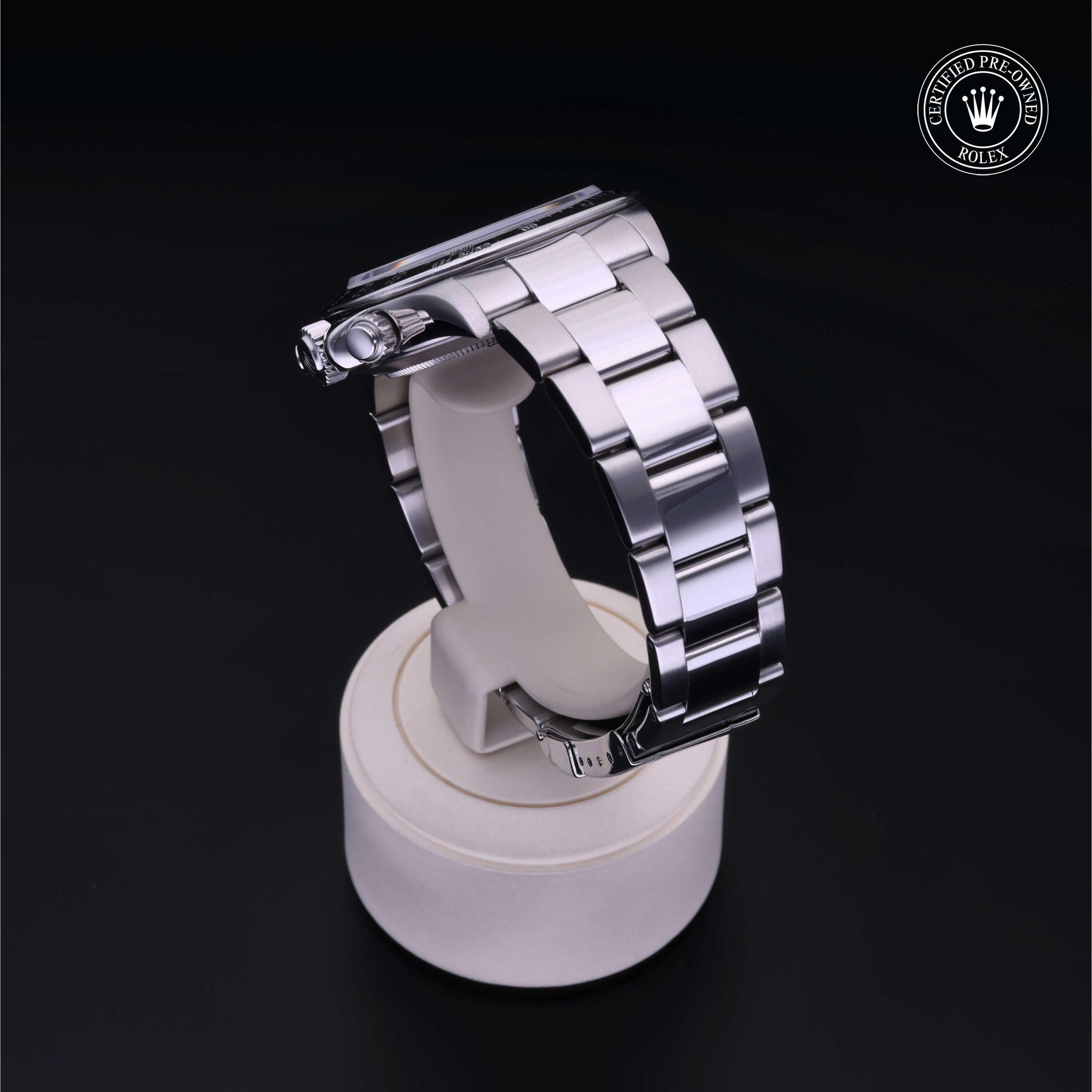 Silver metal luxury watch bracelet displayed on a white stand with a dark background and a Rolex Certified Pre-Owned emblem in the corner, highlighting fine watch craftsmanship.