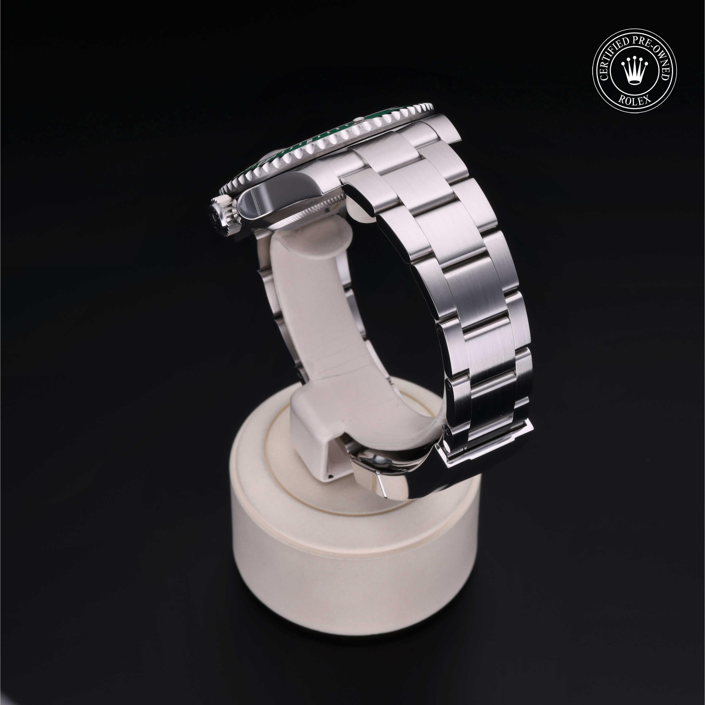 Close-up of a luxury stainless steel Rolex watch with a polished bracelet, displayed on a white stand against a black background, featuring a certified pre-owned Rolex logo.