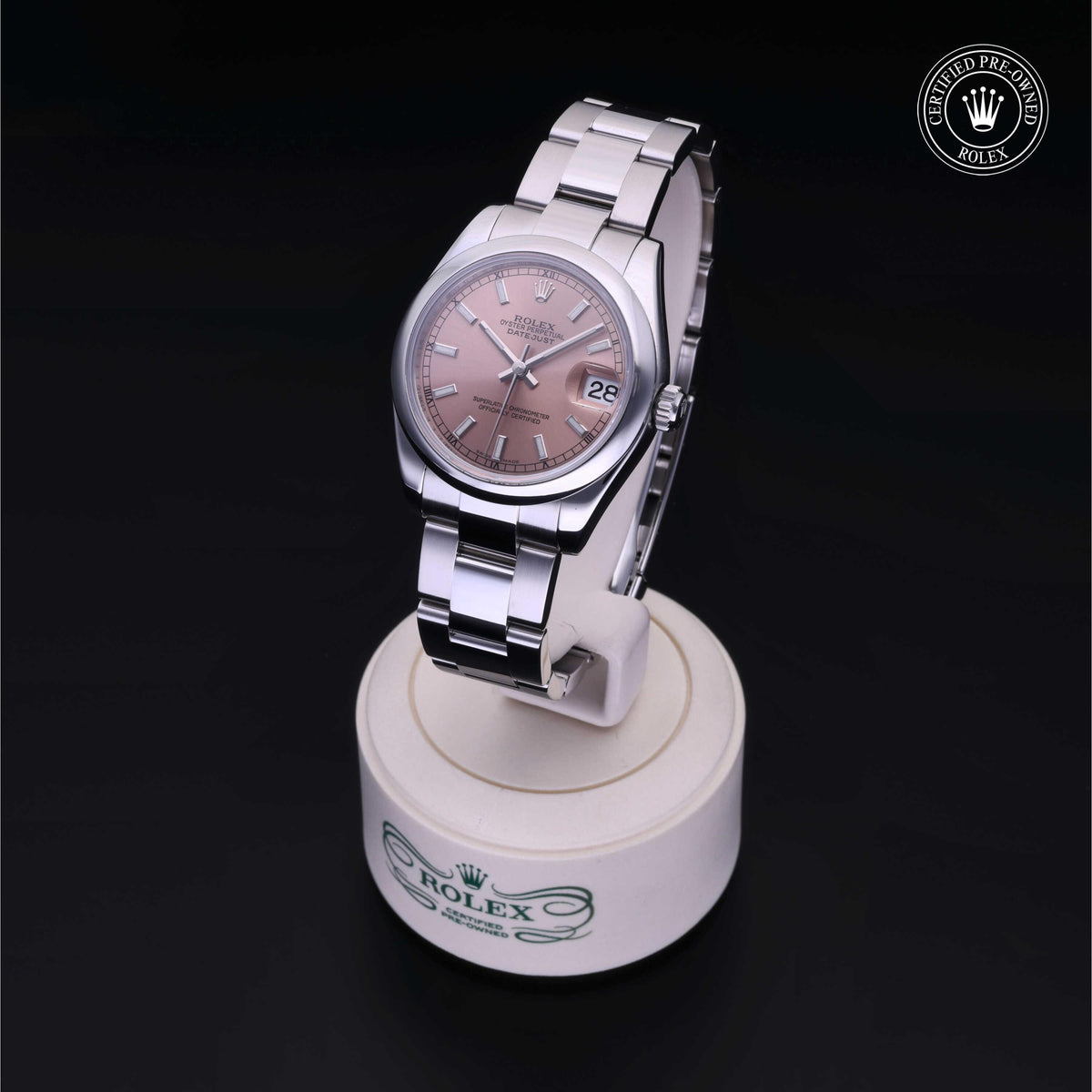 Rolex luxury watch with a pink dial and stainless steel band displayed on a branded stand, featuring a date window and Rolex Certified Pre-Owned seal.