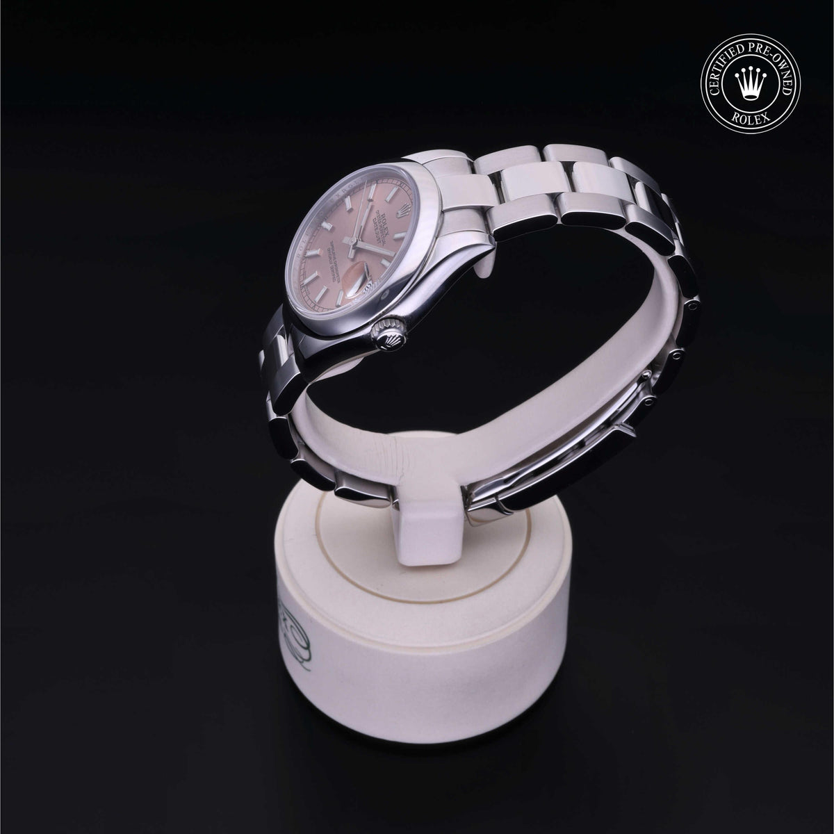 Rolex Certified Pre-Owned stainless steel luxury watch with a pink dial displayed on a white stand against a black background, symbolizing timeless elegance.