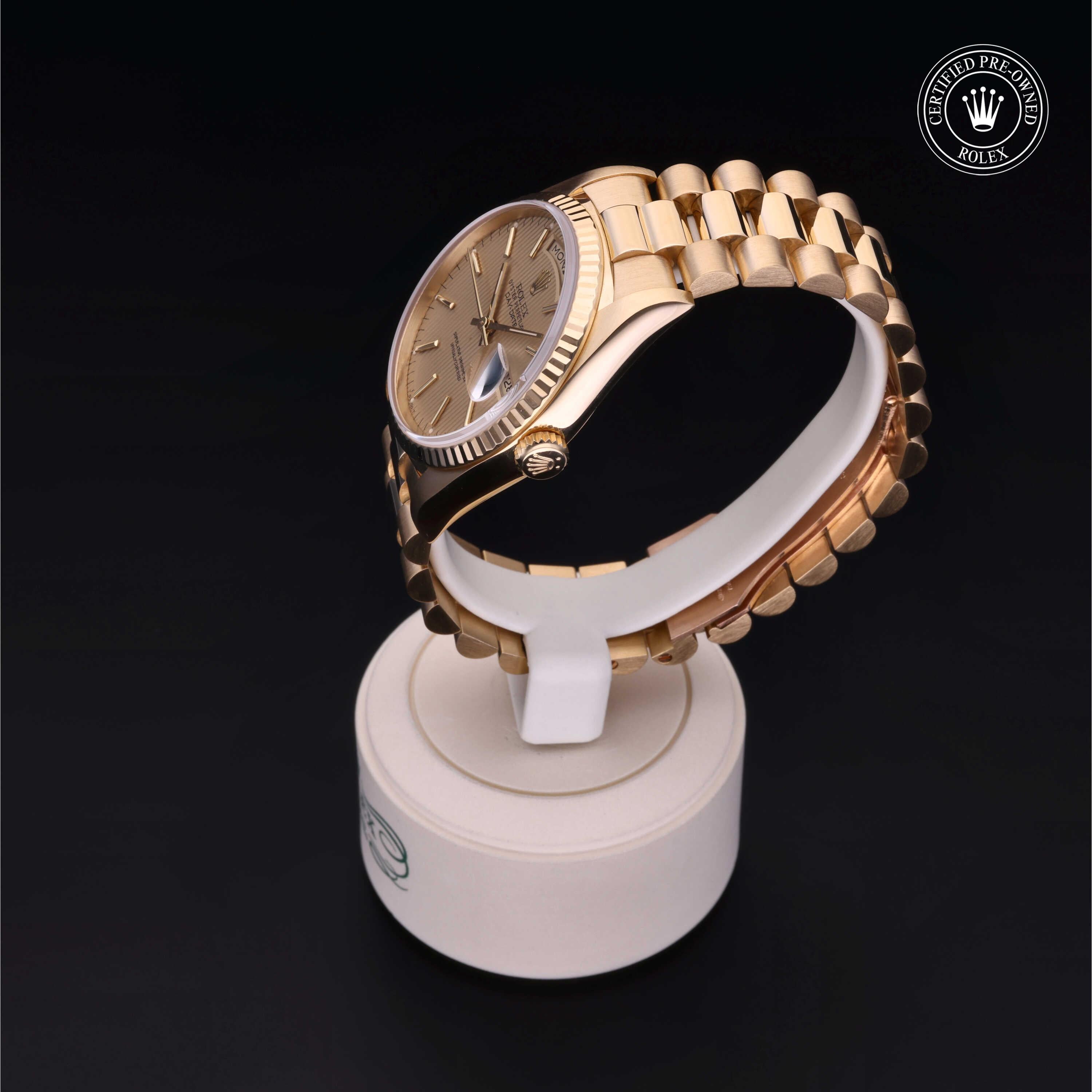 Gold Rolex watch with a fluted bezel and Jubilee bracelet displayed on a white stand against a dark background, featuring the Rolex Certified Pre-Owned logo.