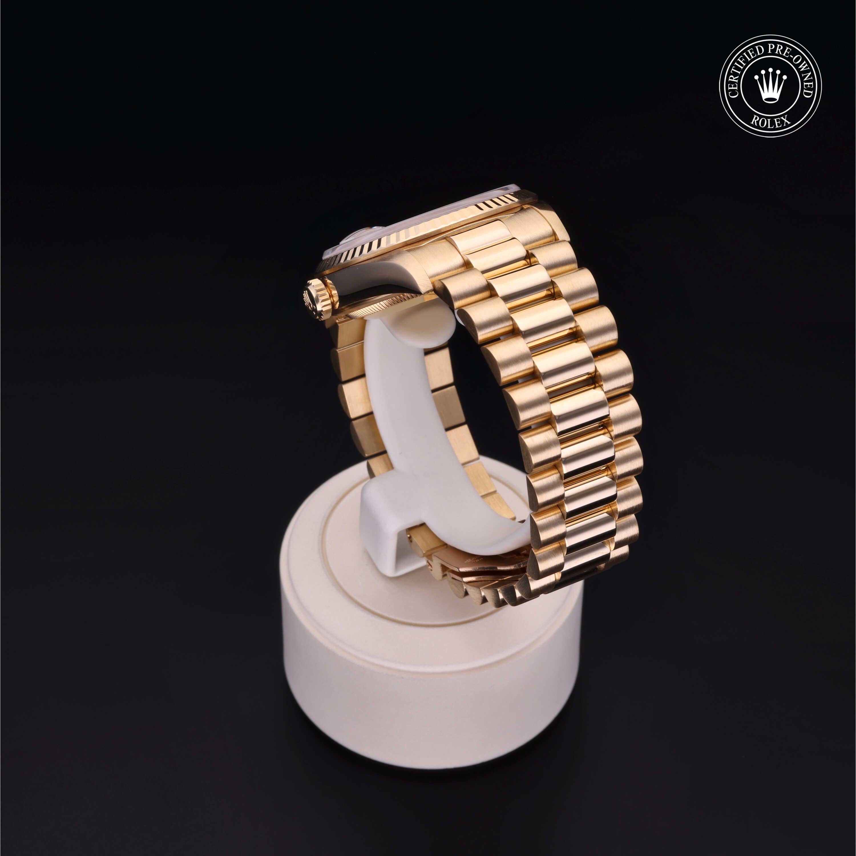 Side view of a gold Rolex watch with a polished bracelet displayed on a white stand against a black background, featuring a certified pre-owned Rolex logo.