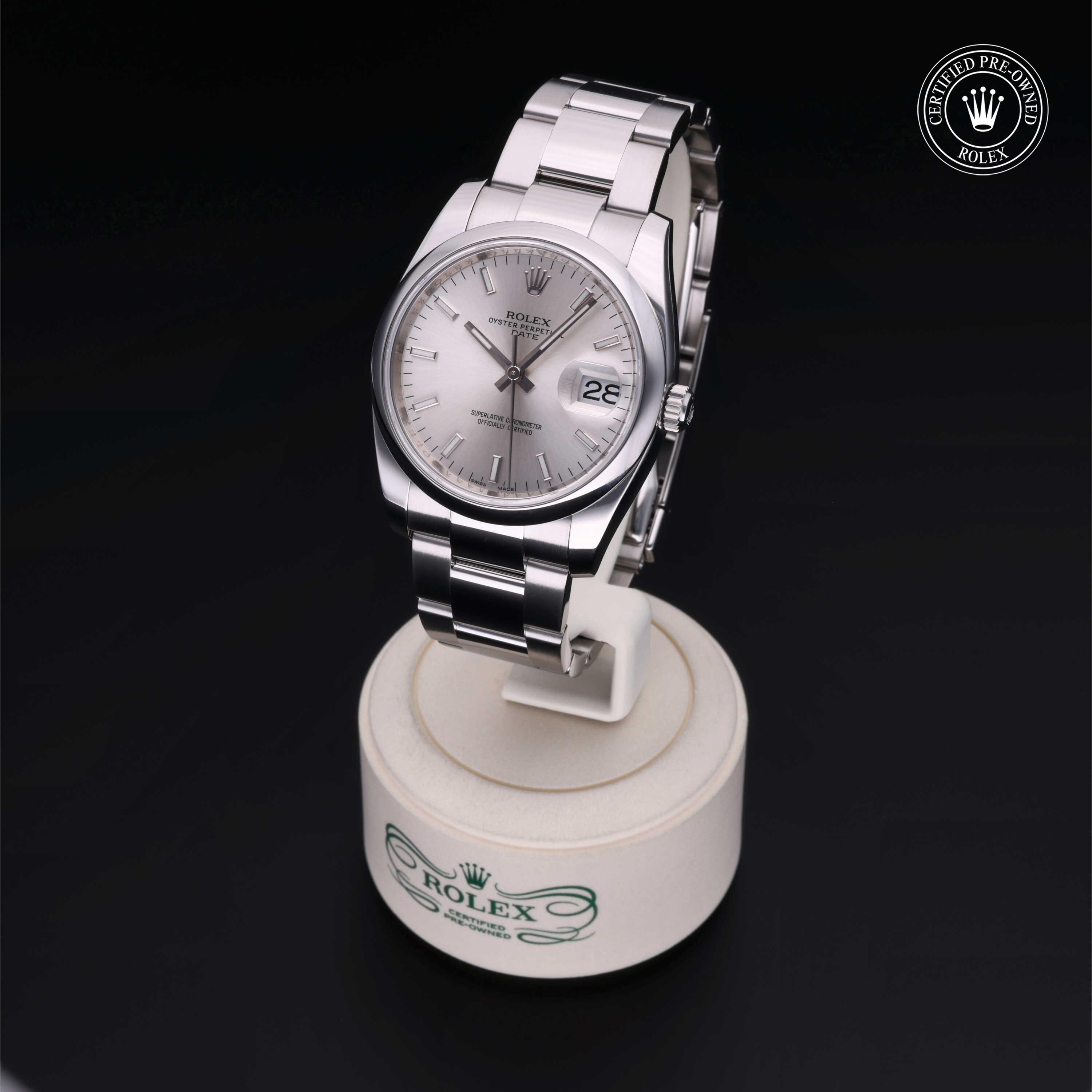 Silver Rolex wristwatch with a metal bracelet displayed on a white stand against a black background, featuring a date window and 