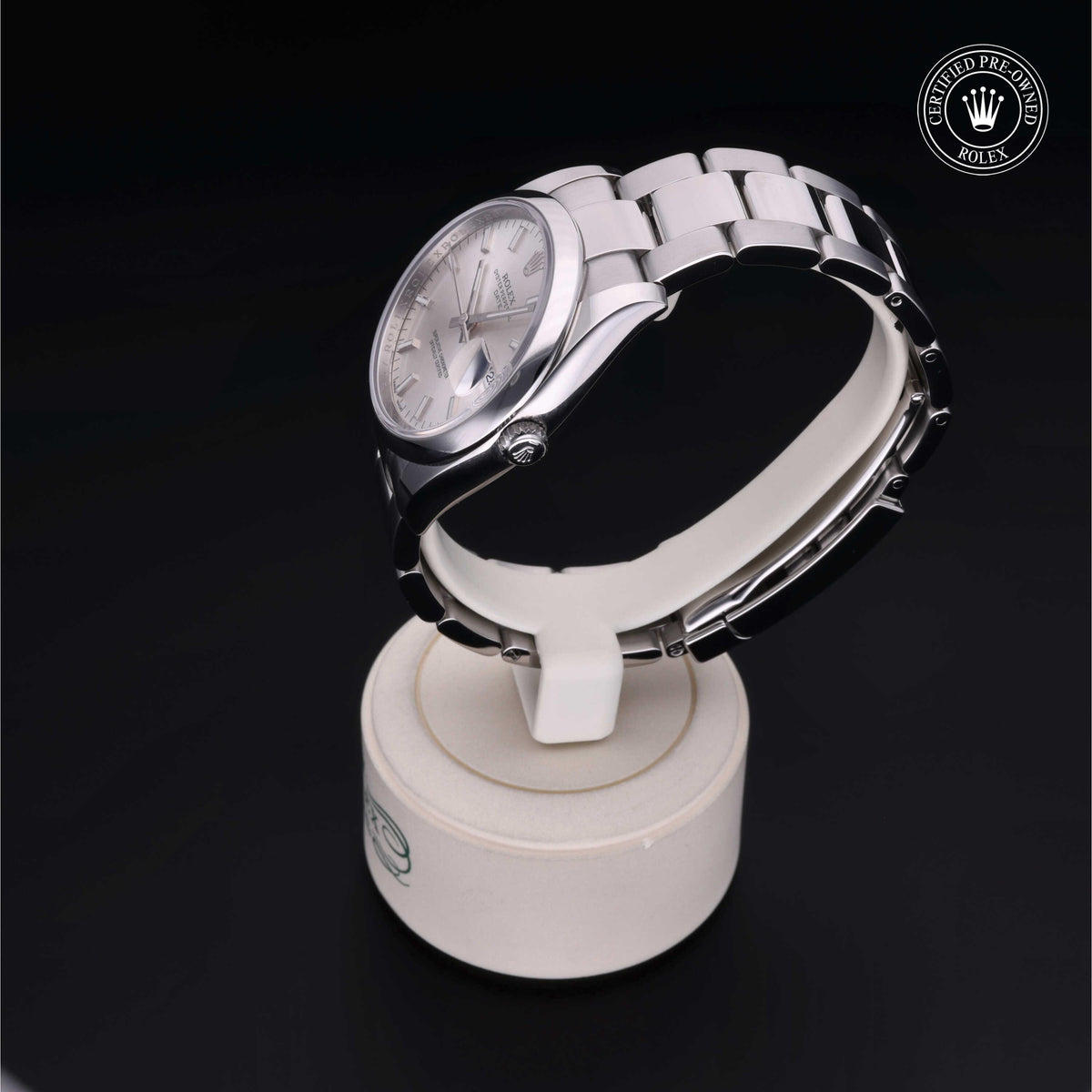 Silver Rolex luxury watch with metal link band displayed on a white stand, featuring a Rolex Certified Pre-Owned logo on a black background, highlighting fine craftsmanship.