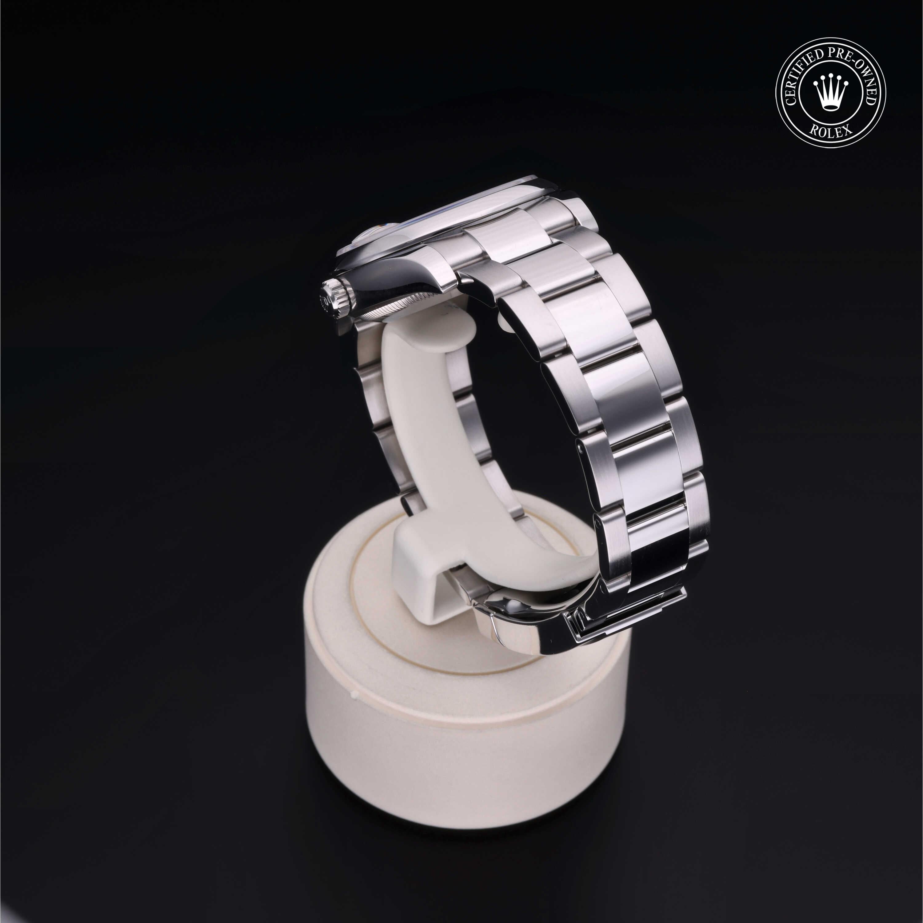 Stainless steel luxury watch bracelet displayed on a round white stand with Rolex Certified Pre-Owned logo in the corner, highlighting fine craftsmanship and quality.