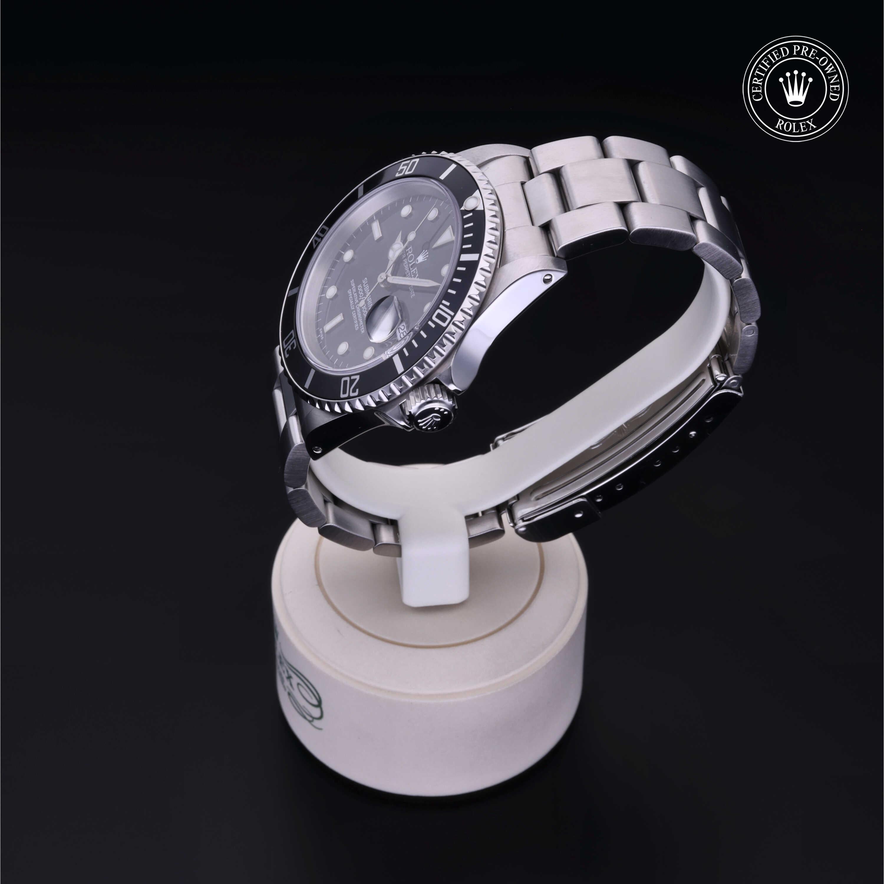 Rolex luxury watch with stainless steel band and black bezel displayed on a white stand against a black background, showcasing Henne Jewelers' expertise in certified pre-owned Rolex watches.