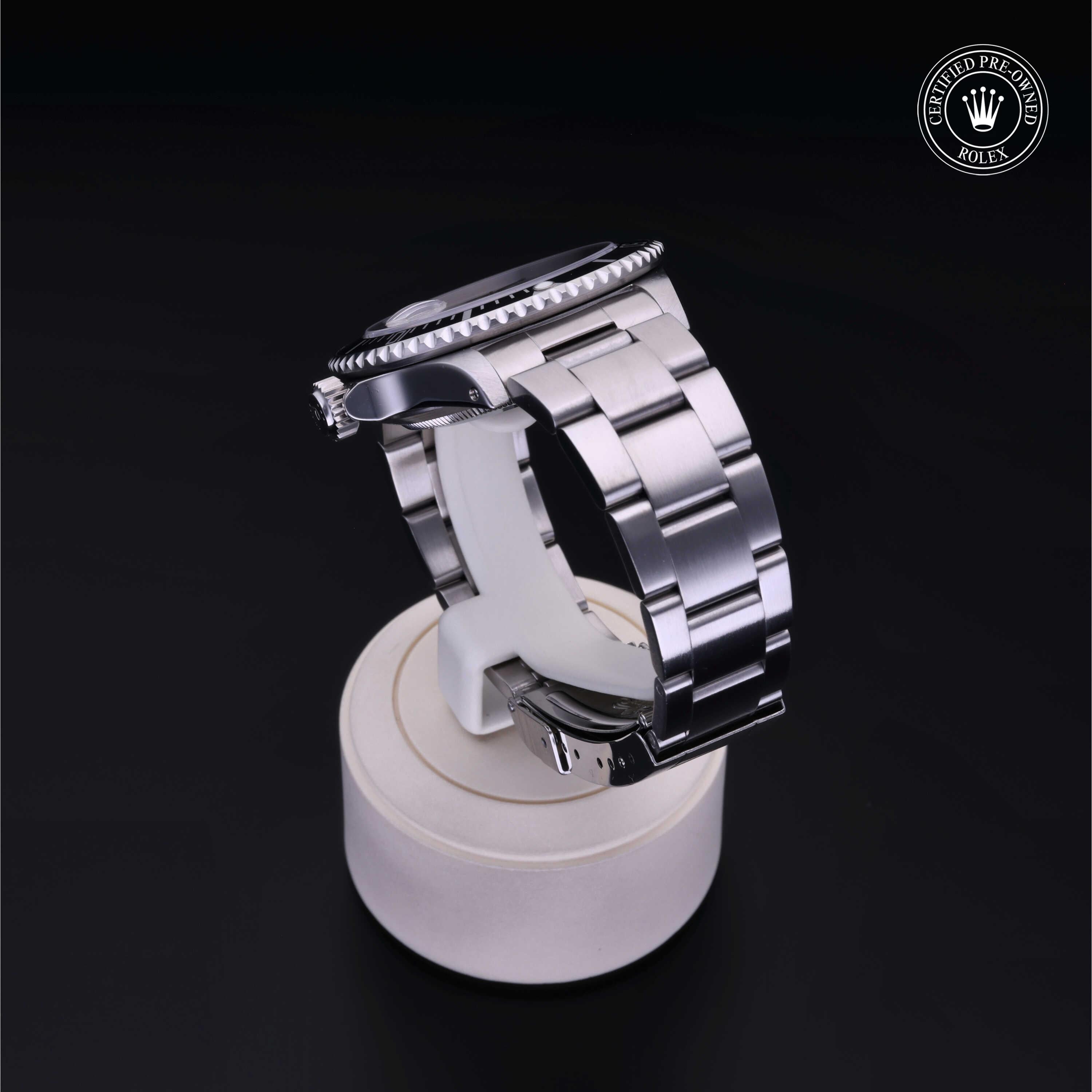 Close-up of a luxury stainless steel Rolex watch displayed on a white stand against a black background, featuring the Rolex Certified Pre-Owned logo.