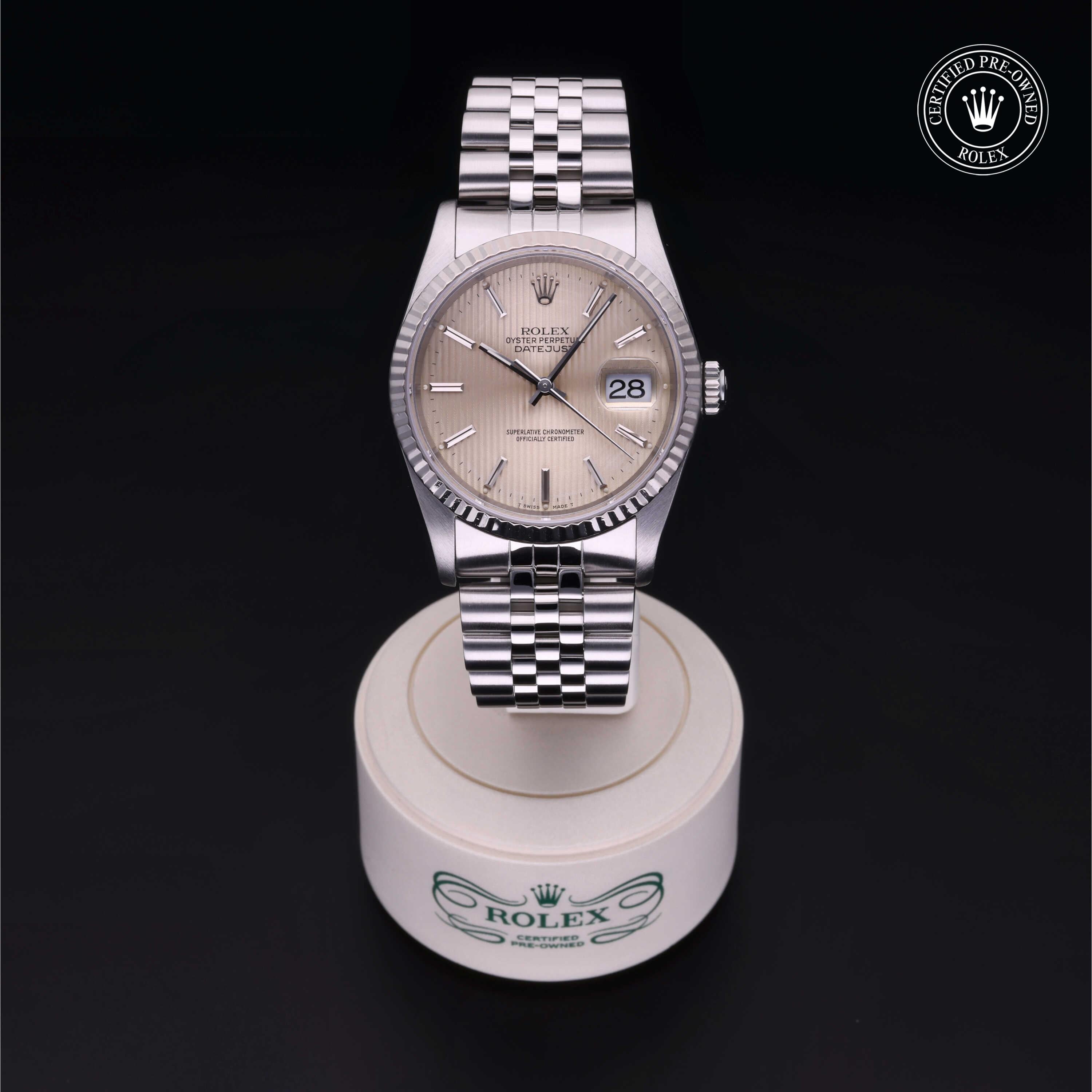 Rolex Certified Pre-Owned silver watch with a jubilee bracelet displayed on a branded stand against a black background, highlighting luxury craftsmanship.