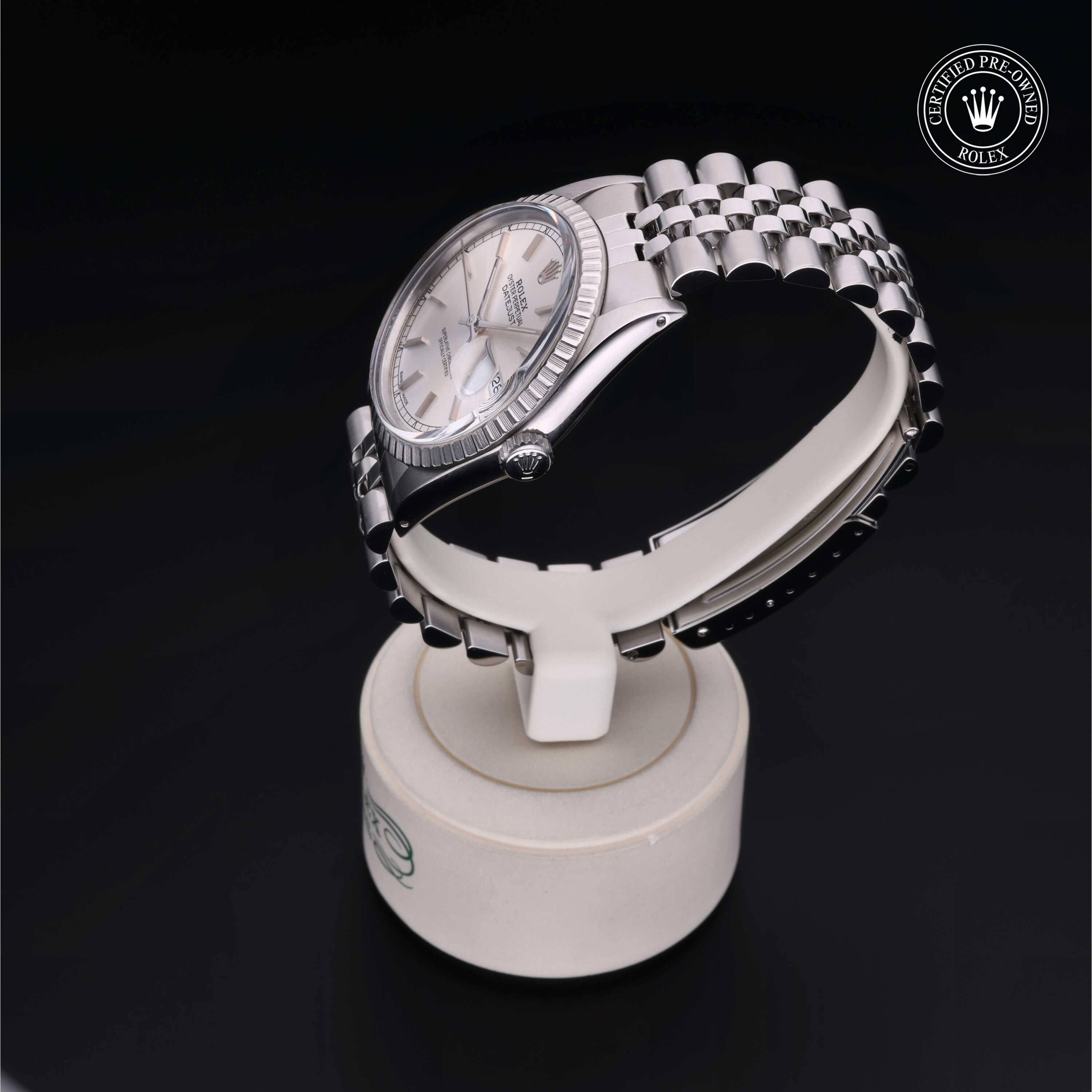 Silver Rolex wristwatch with a fluted bezel and jubilee bracelet displayed on a round white stand against a black background, featuring a Certified Pre-Owned Rolex badge.