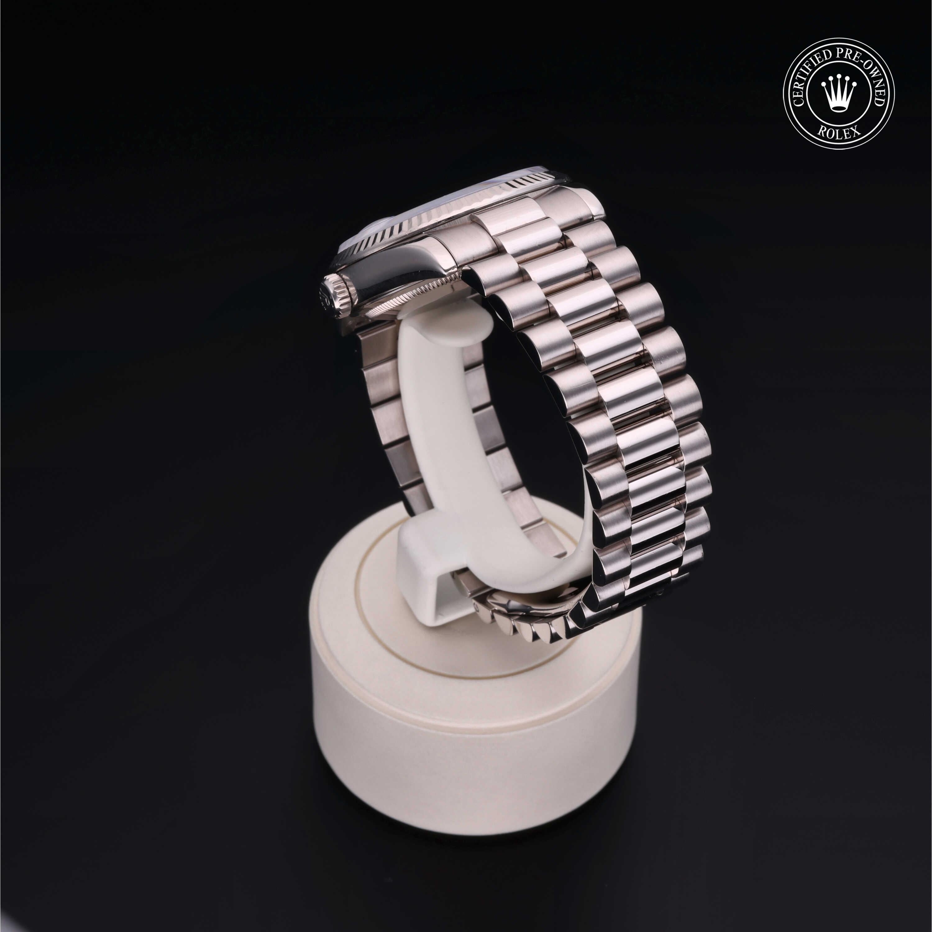 A polished stainless steel Rolex watch with a linked bracelet displayed on a white stand against a black background, featuring a Certified Pre-Owned Rolex logo in the corner.