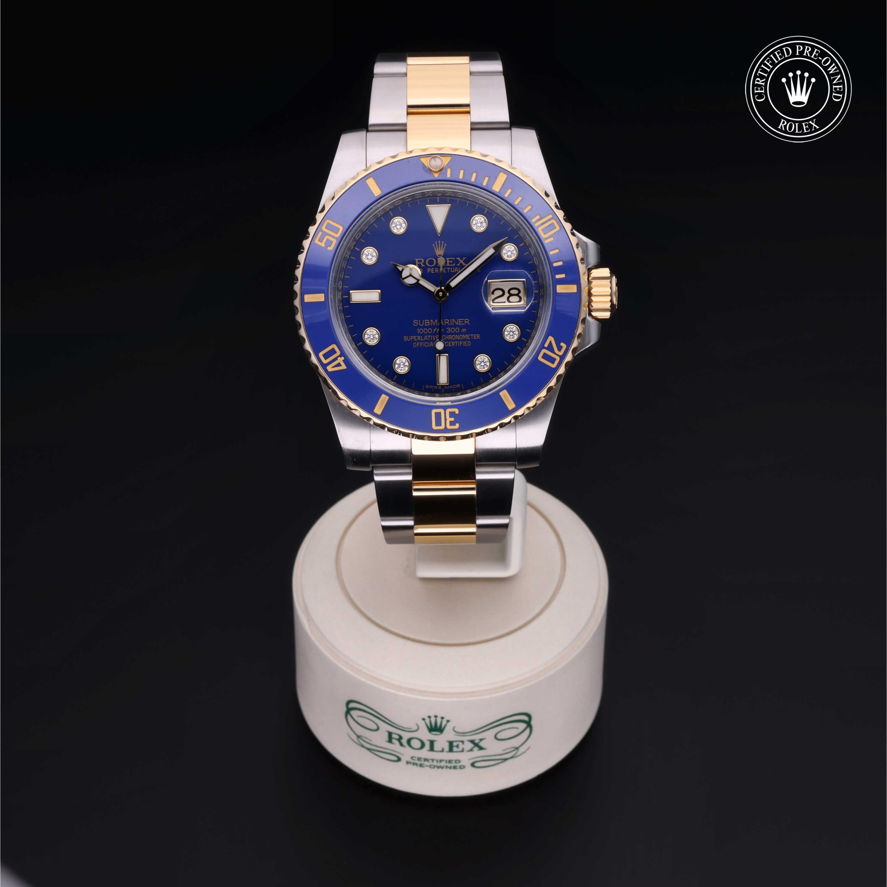 Rolex two-tone luxury watch with blue dial and gold accents displayed on a branded stand, featuring a date window and certified pre-owned Rolex emblem.