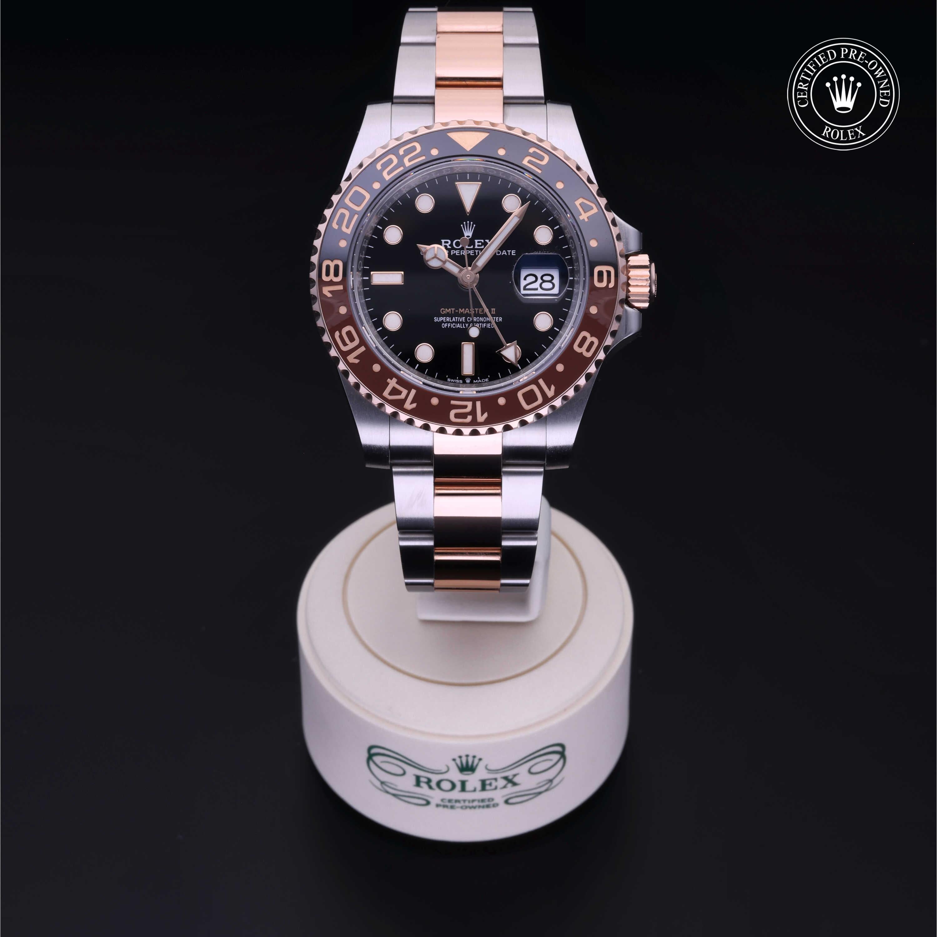 Rolex GMT-Master II watch with two-tone stainless steel and rose gold bracelet, black dial, date display, and rotating bezel, showcased on a branded stand.