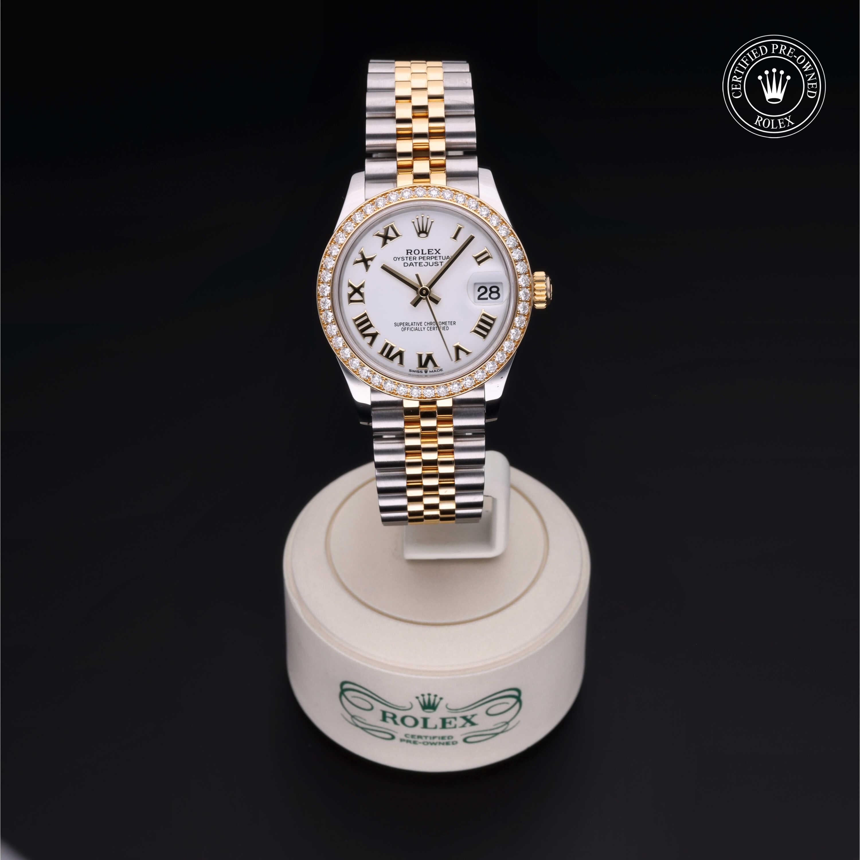 Rolex wristwatch with a two-tone gold and silver bracelet, diamond bezel, white dial with black Roman numerals, displayed on a branded stand marked Rolex Certified Pre-Owned.