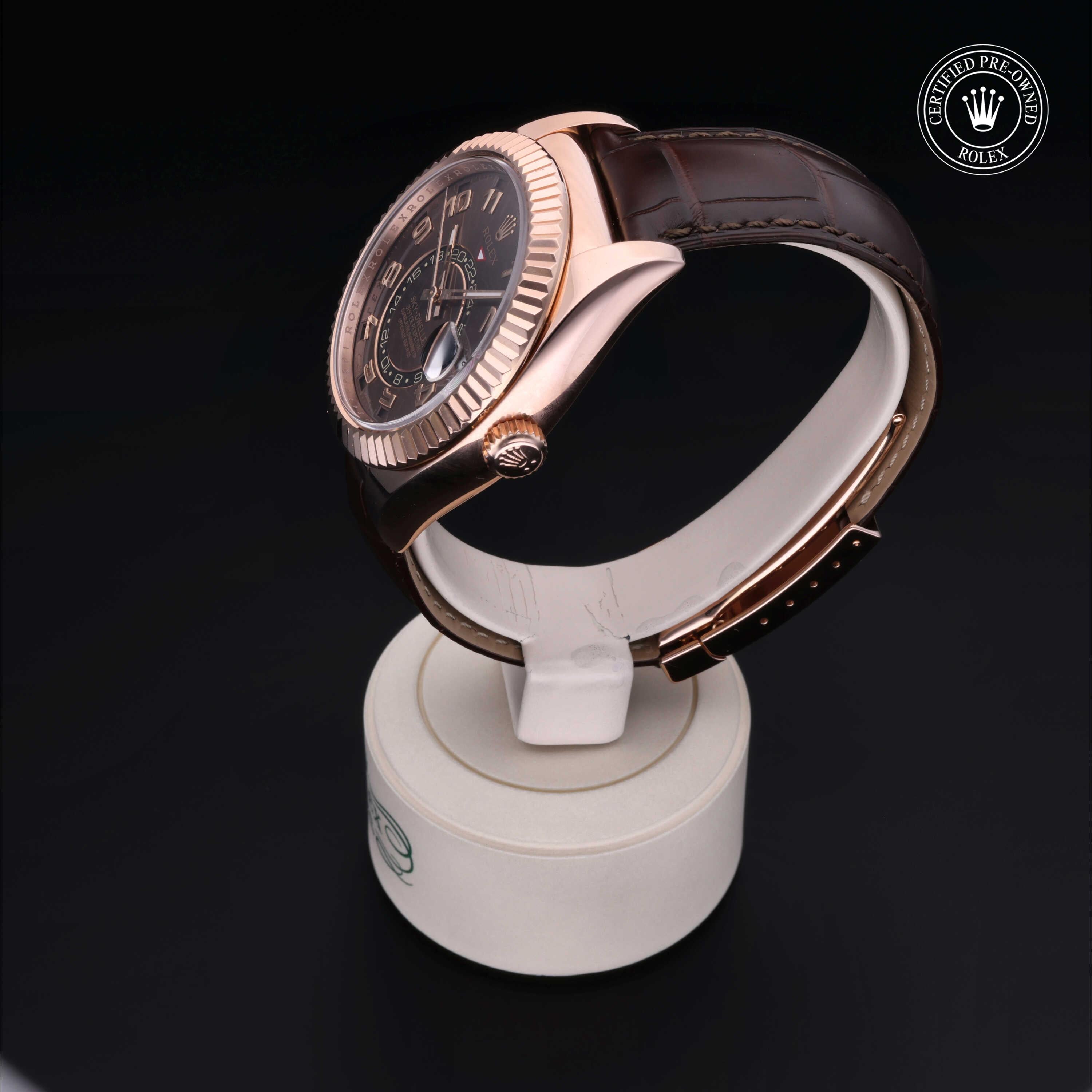 Side view of a luxury watch with a rose gold bezel and brown leather strap displayed on a white stand against a black background, featuring a certified pre-owned Rolex logo.