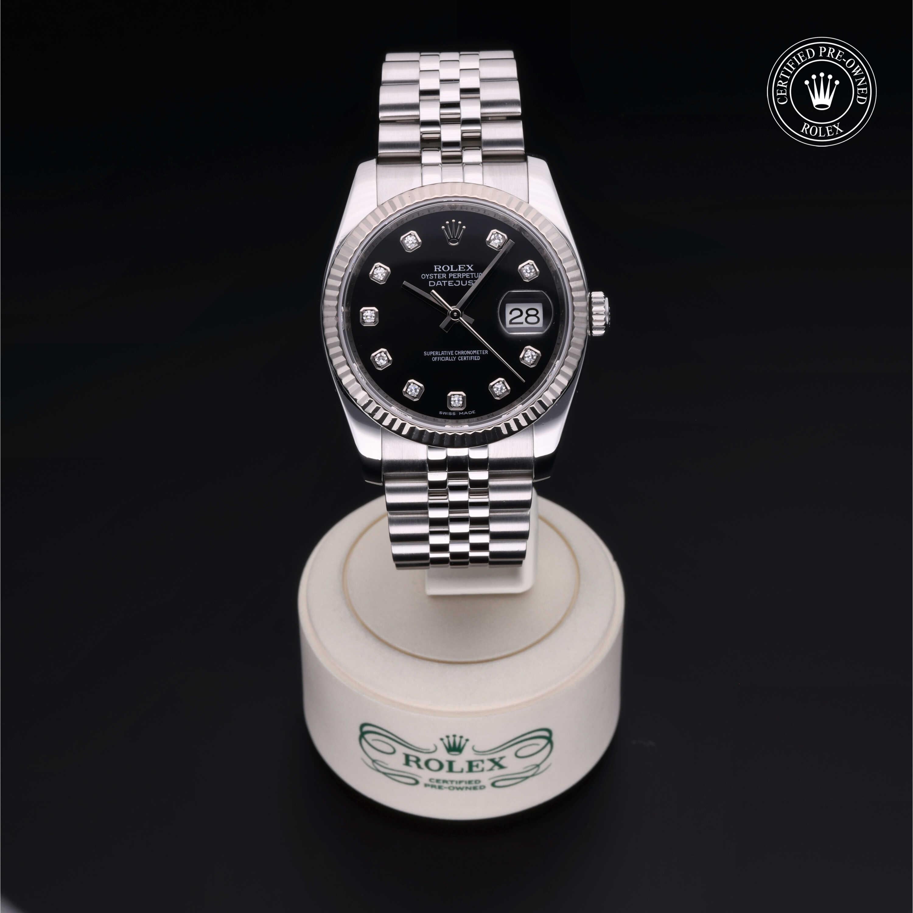 Rolex stainless steel luxury watch with black dial and diamond hour markers displayed on a branded stand, featuring a certified pre-owned Rolex logo.